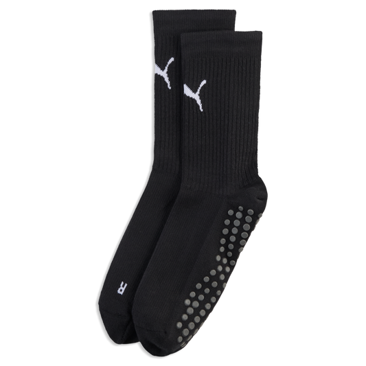 A pair of black crew socks with white Puma logos, ribbed ankles, and grey non-slip grip dots on the soles, set against a black background.