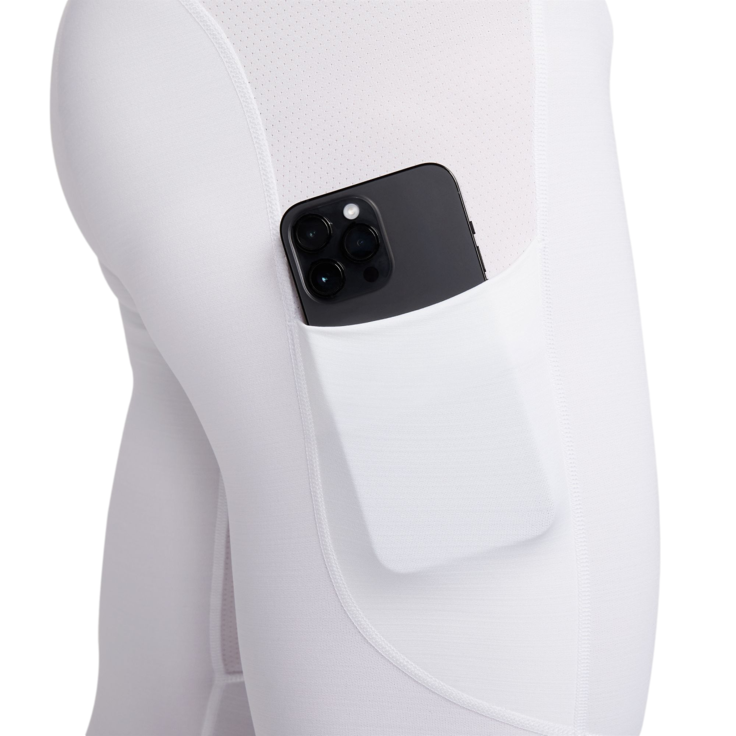 Close-up of a black smartphone tucked into the side pocket of white athletic leggings.