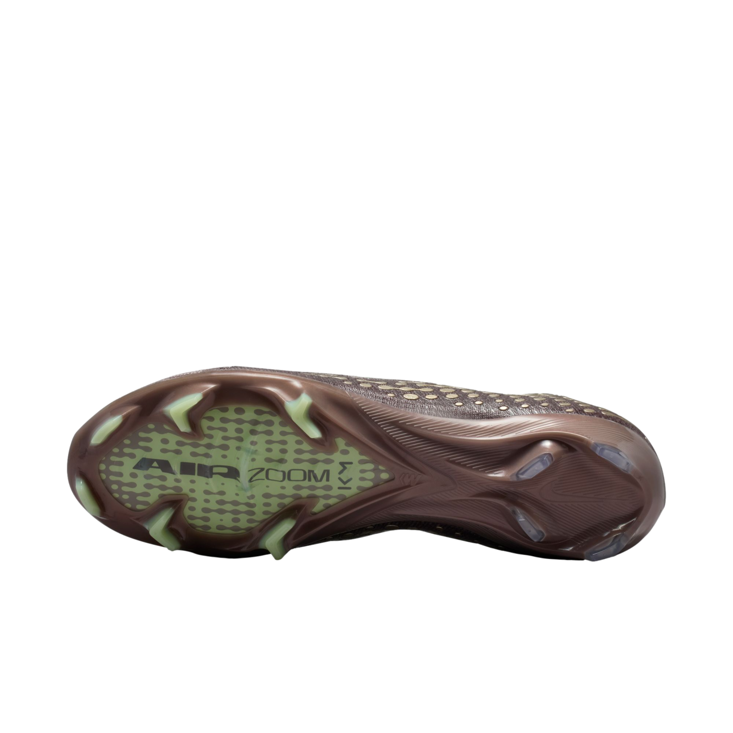Sole of a bronze Nike soccer cleat with lime green studs and "AIR ZOOM KM" branding on a translucent forefoot plate, against a black background.