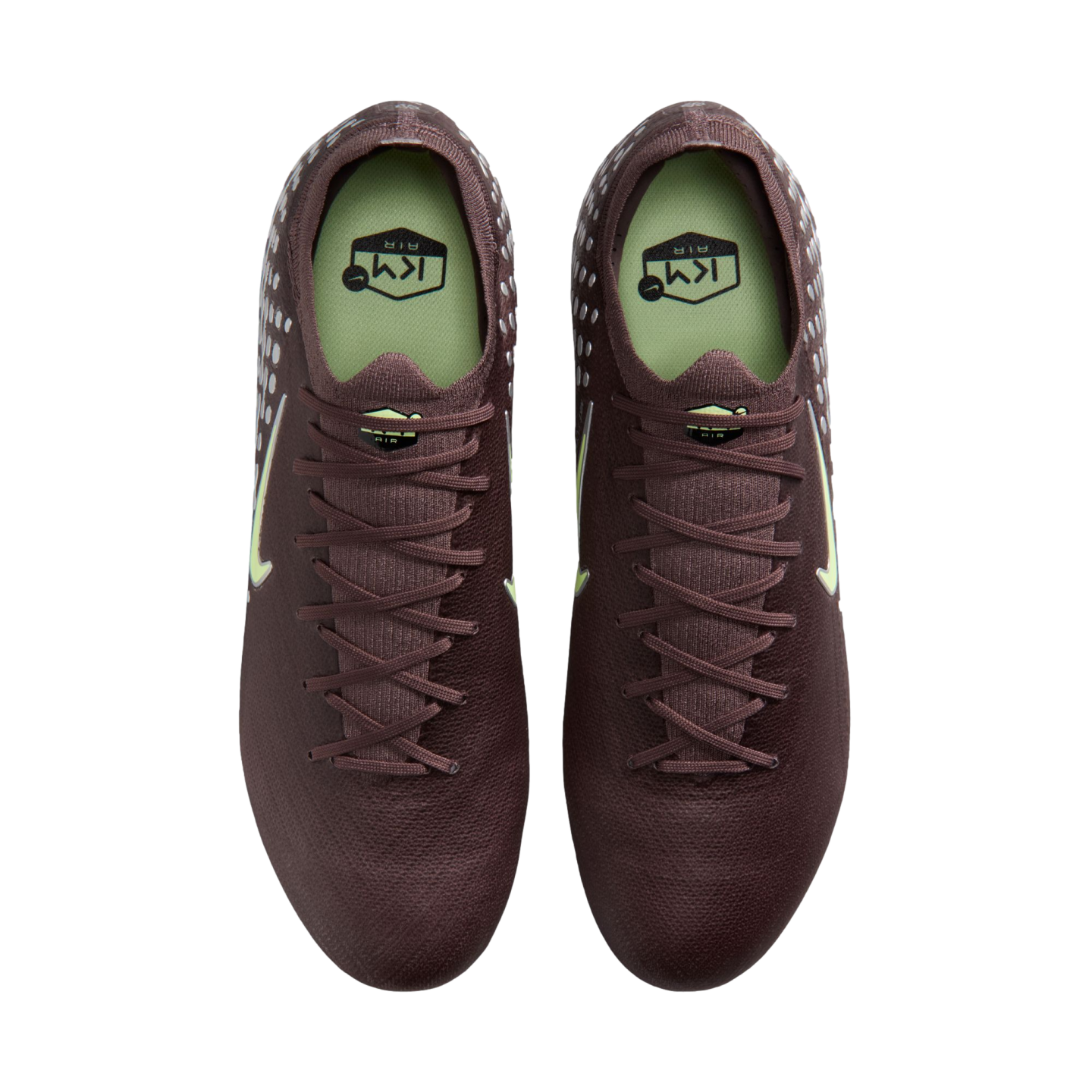 Overhead view of a pair of dark maroon Nike soccer cleats with light green accents and insoles, set against a black background.