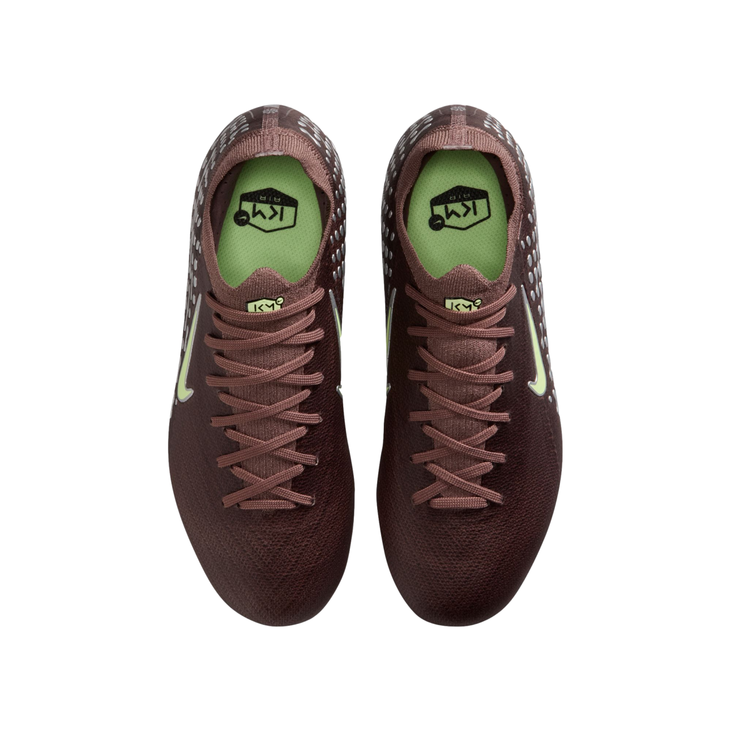 Overhead view of deep burgundy Nike soccer cleats with pale green accents and "KM" branding, set against a black background.
