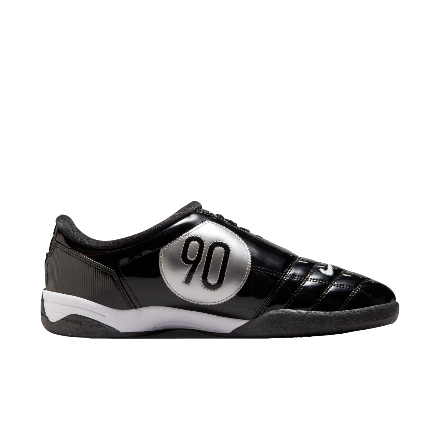 Side profile of a black glossy Nike Total 90 indoor soccer shoe featuring a large silver circular "90" logo and a white midsole.