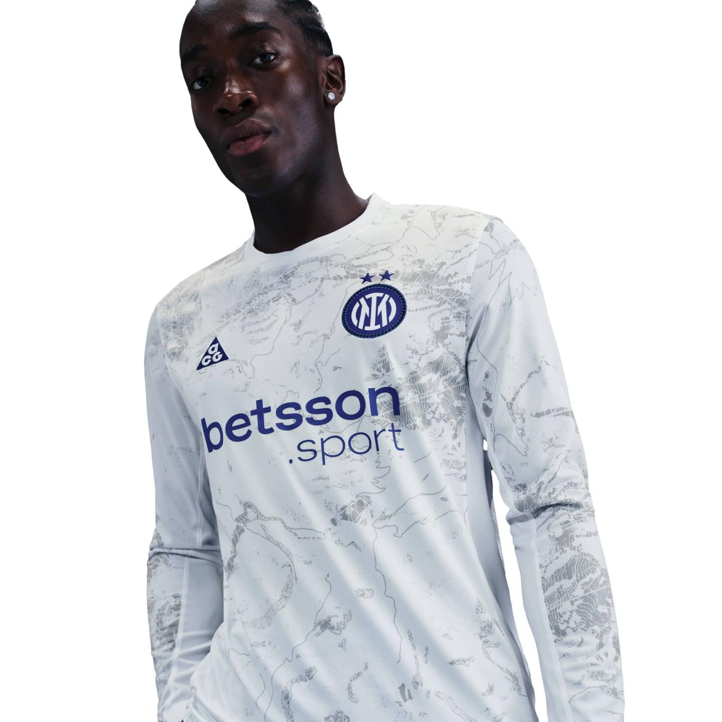 A man wears a long-sleeved white Inter Milan jersey with a gray marbled design and "betsson.sport" logo, set against a black background.