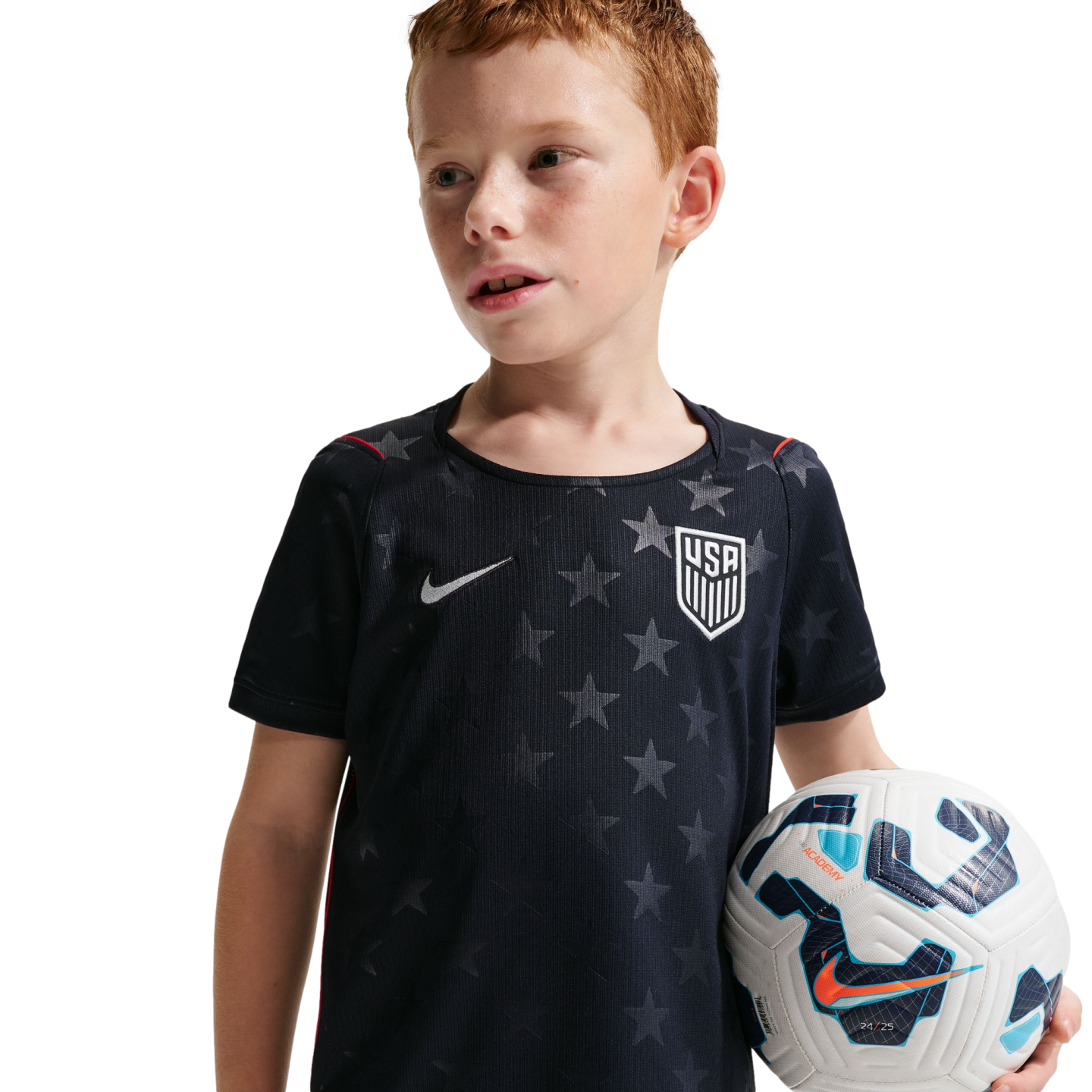 A young boy with red hair wearing a navy blue USA national team soccer jersey with a star pattern, holding a soccer ball.