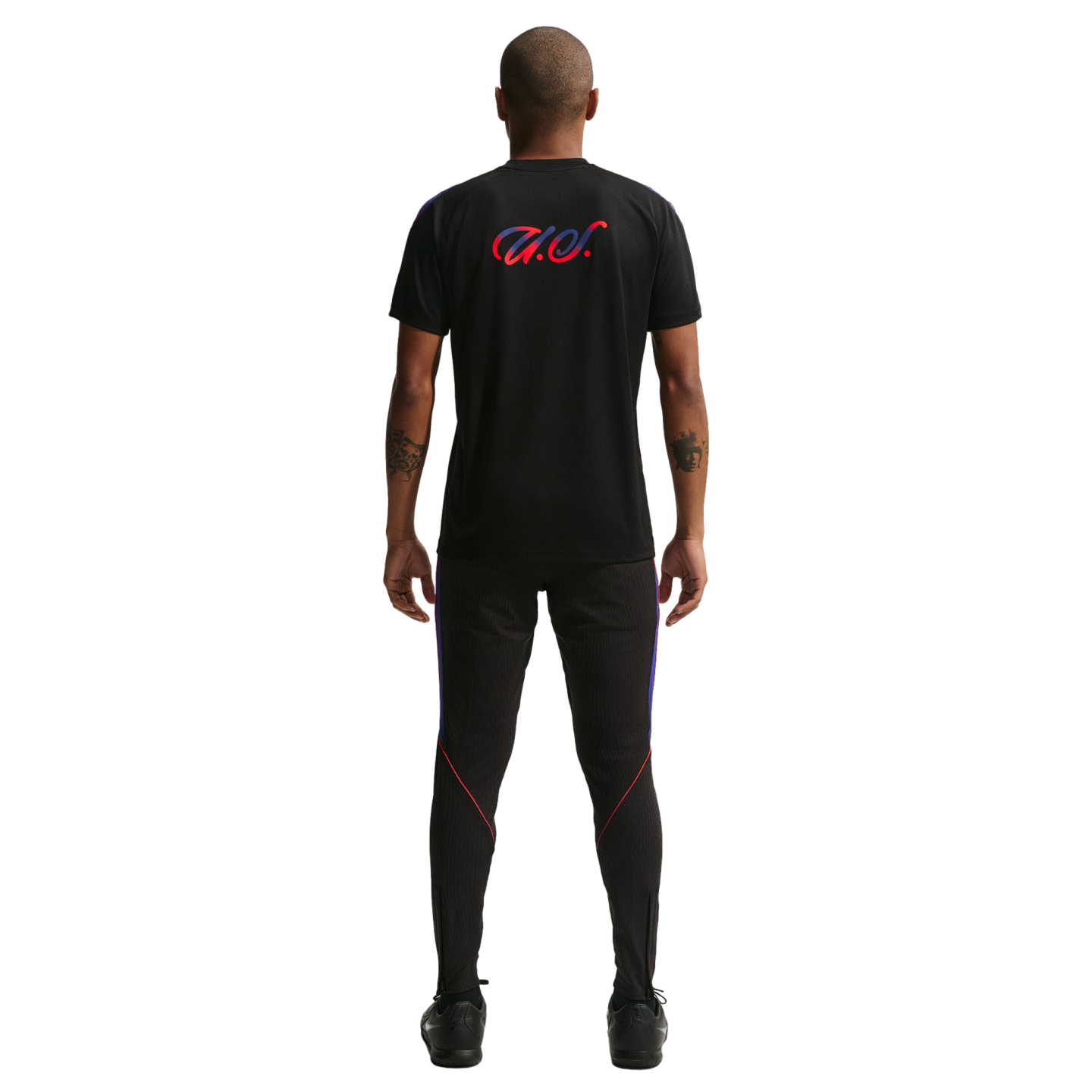 Back view of a man wearing a black t-shirt with a red and blue "U.S." script and matching black athletic pants against a black background.