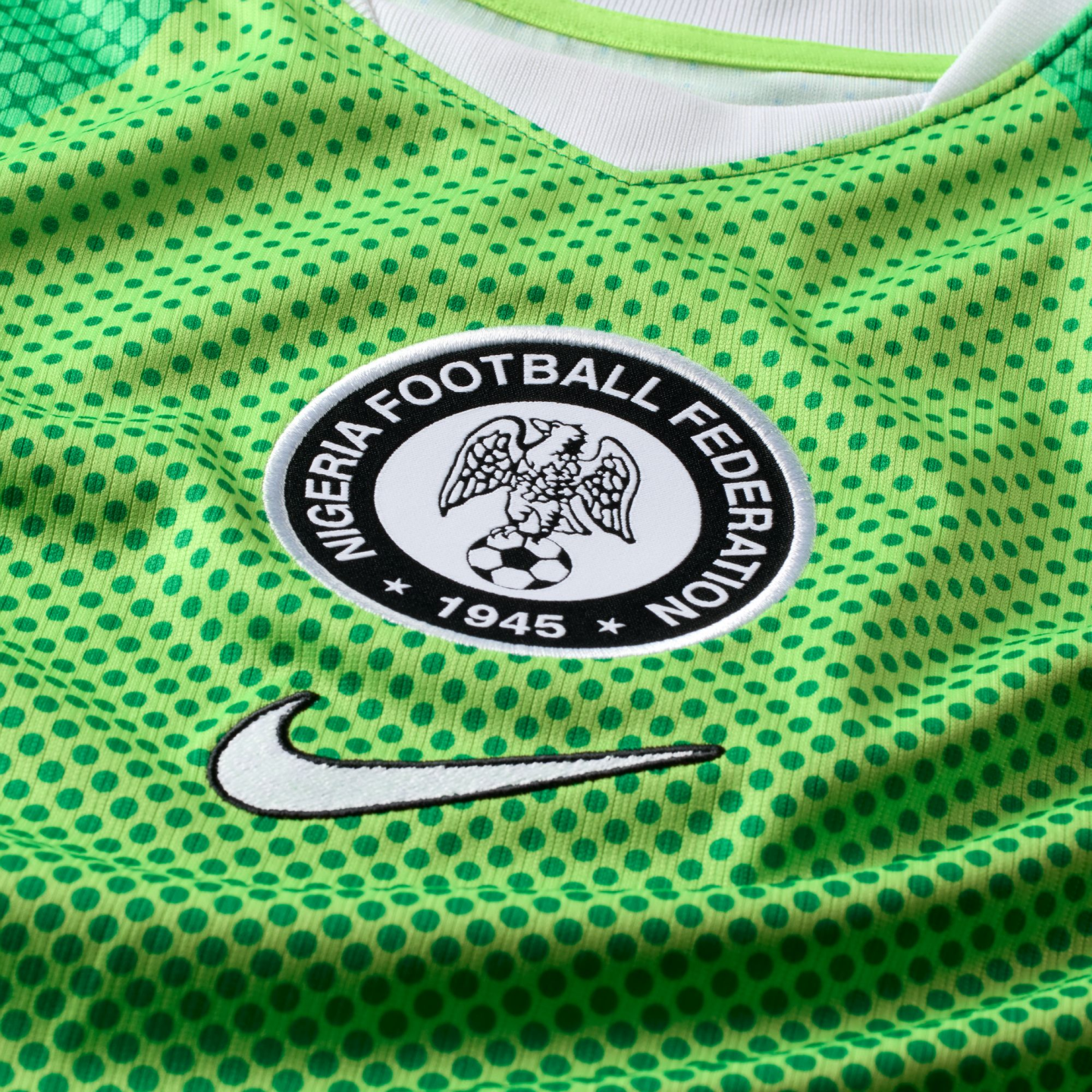 Close-up of a green Nigeria soccer jersey with a polka dot pattern, featuring the Nigeria Football Federation crest and a white Nike swoosh.