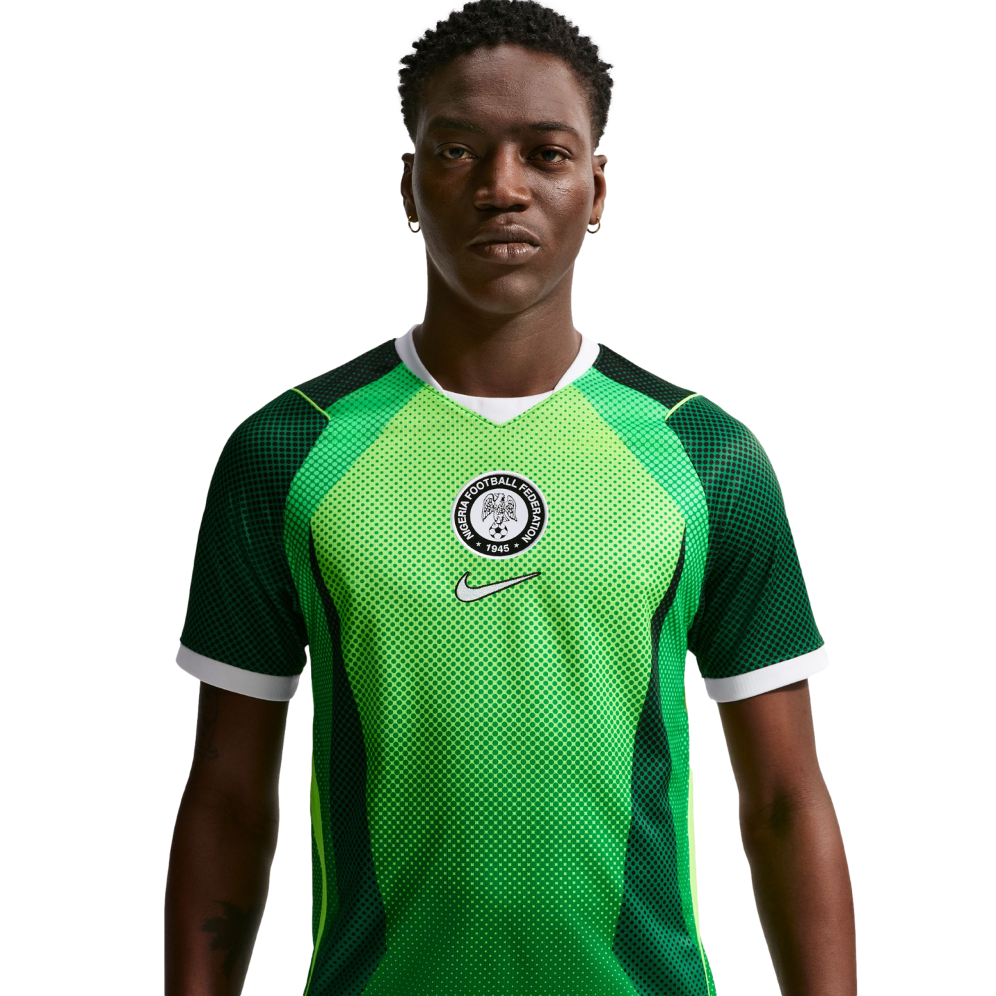 Man wearing a green Nigeria national football team home jersey with a circular federation crest and white Nike swoosh, set against a black background.