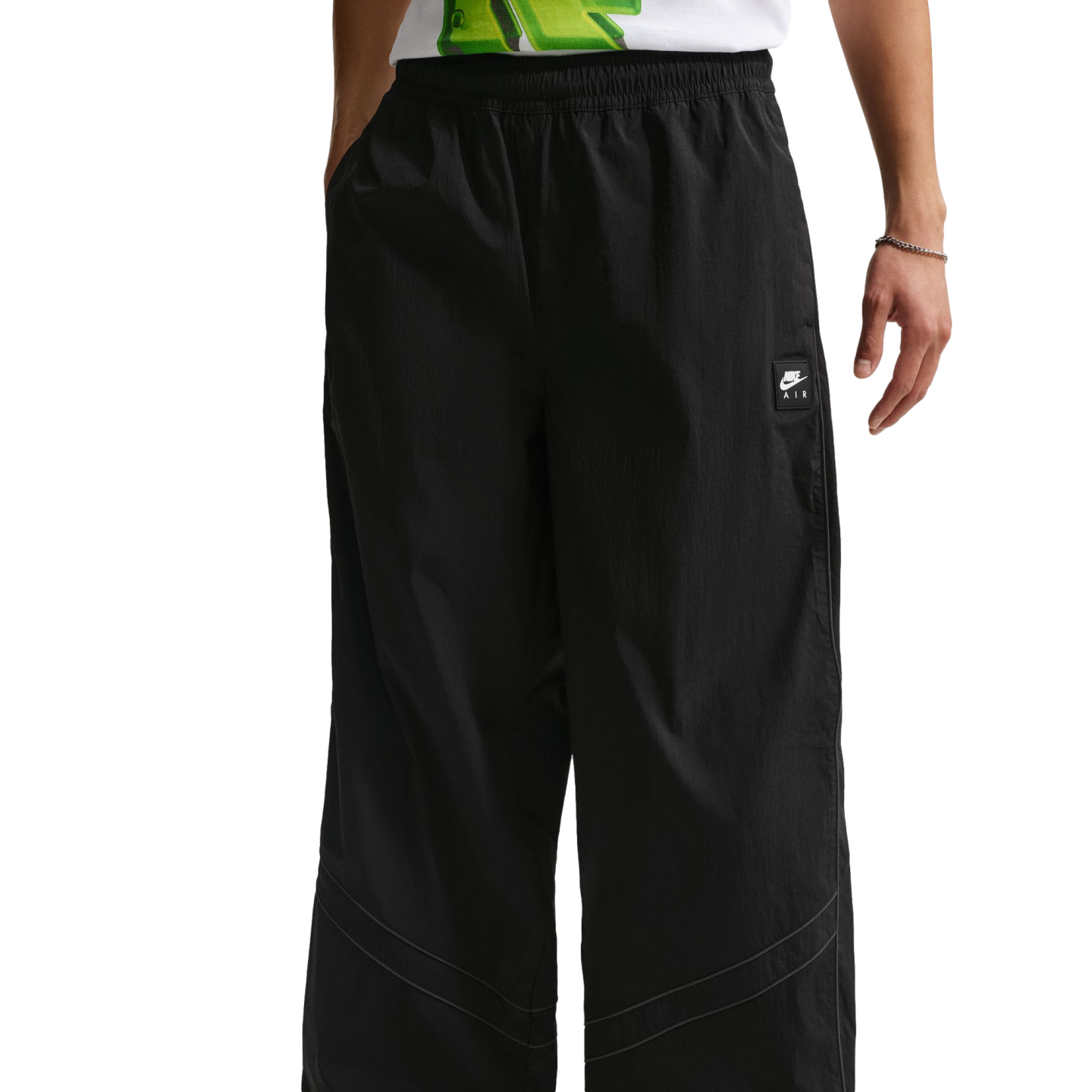 A person wears black wide-leg Nike Air trousers with thin grey curved piping around the knees.