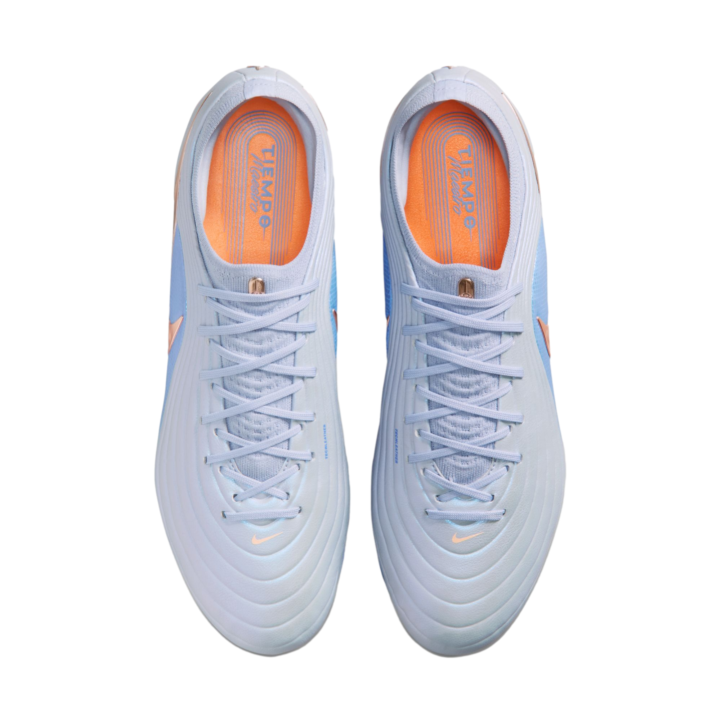 Top-down view of a pair of light blue Nike Tiempo soccer cleats with orange insoles, set against a solid black background.