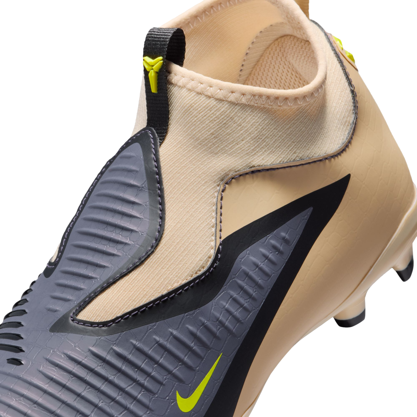 Close-up of a tan Nike soccer cleat featuring a textured grey striking zone, lime green swoosh, and a sock-like ankle collar.