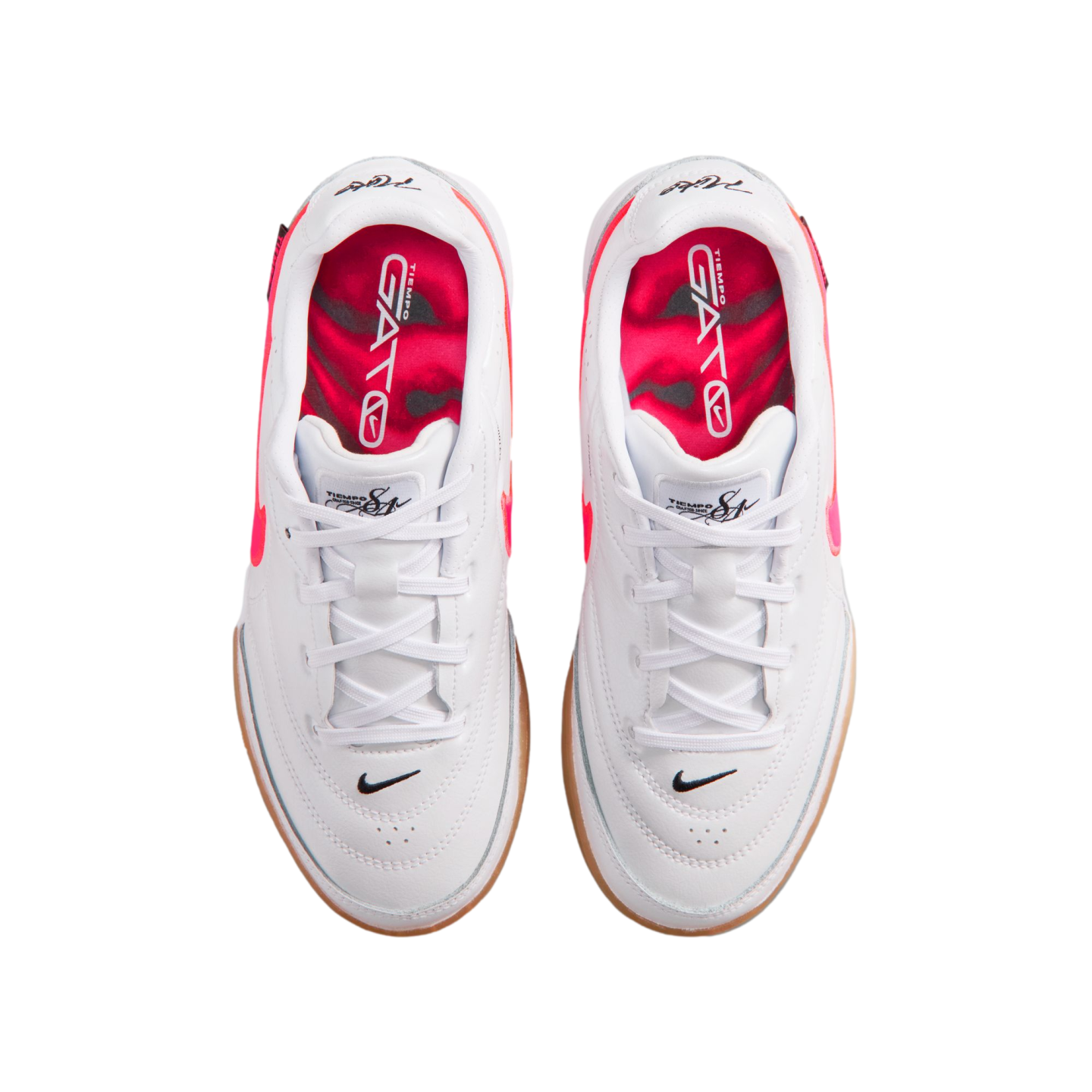 Top-down view of white Nike Tiempo Gato indoor soccer shoes with bright pink interiors, white laces, and gum outsoles.