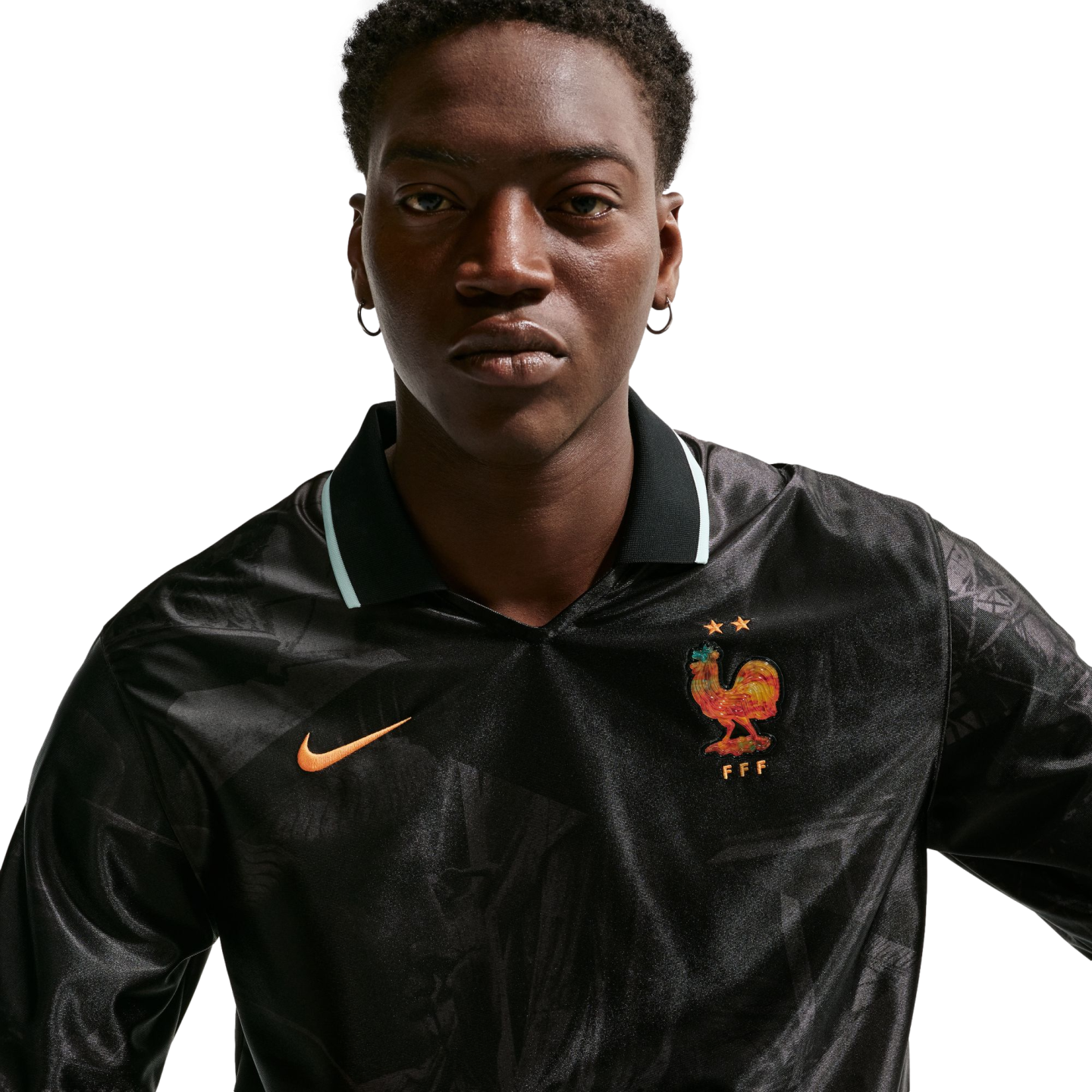 A man in a black long-sleeved Nike France jersey with a colorful rooster crest and two stars, set against a white background.