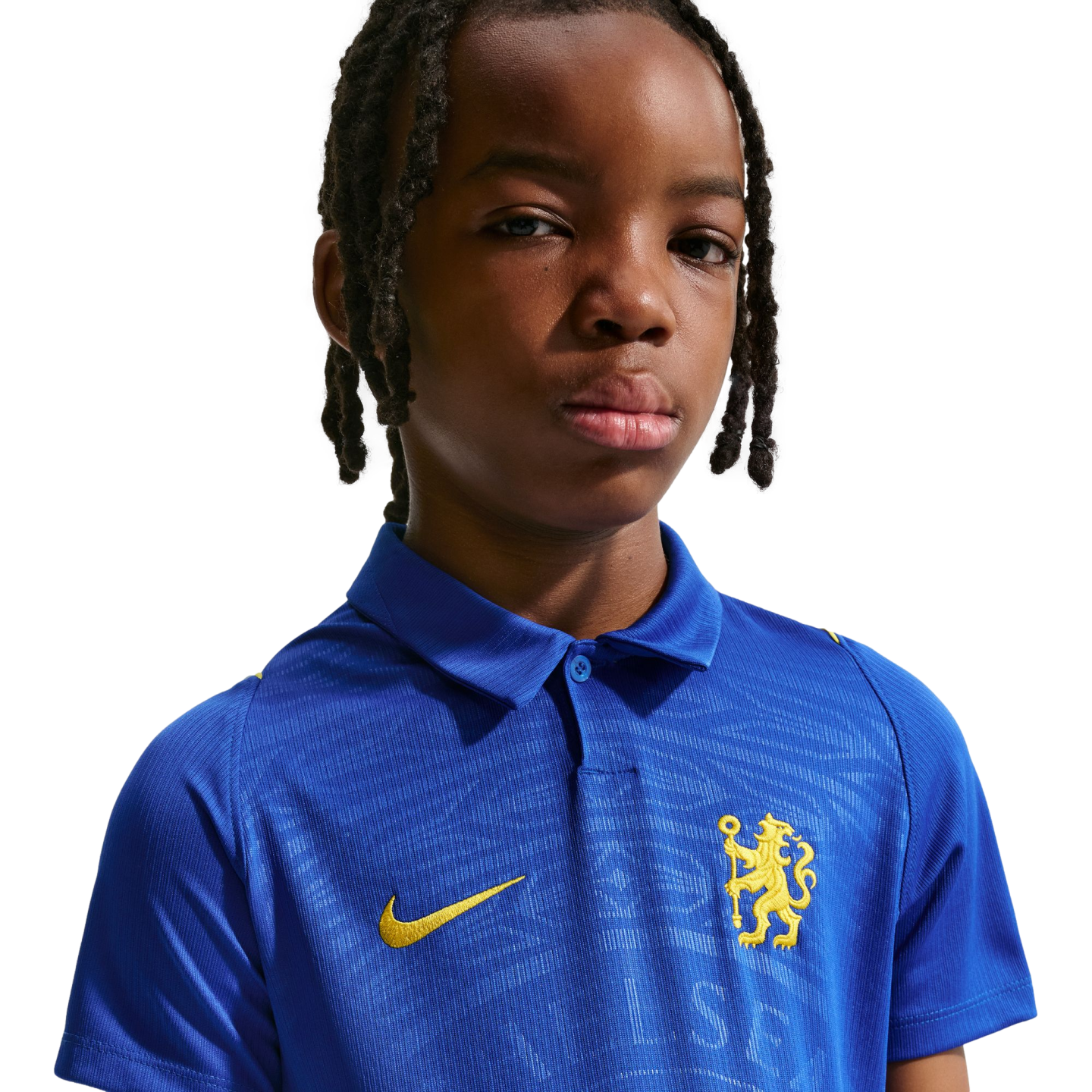 Portrait of a young person with braided hair wearing a blue Chelsea FC polo shirt with a yellow lion crest, against a white background.