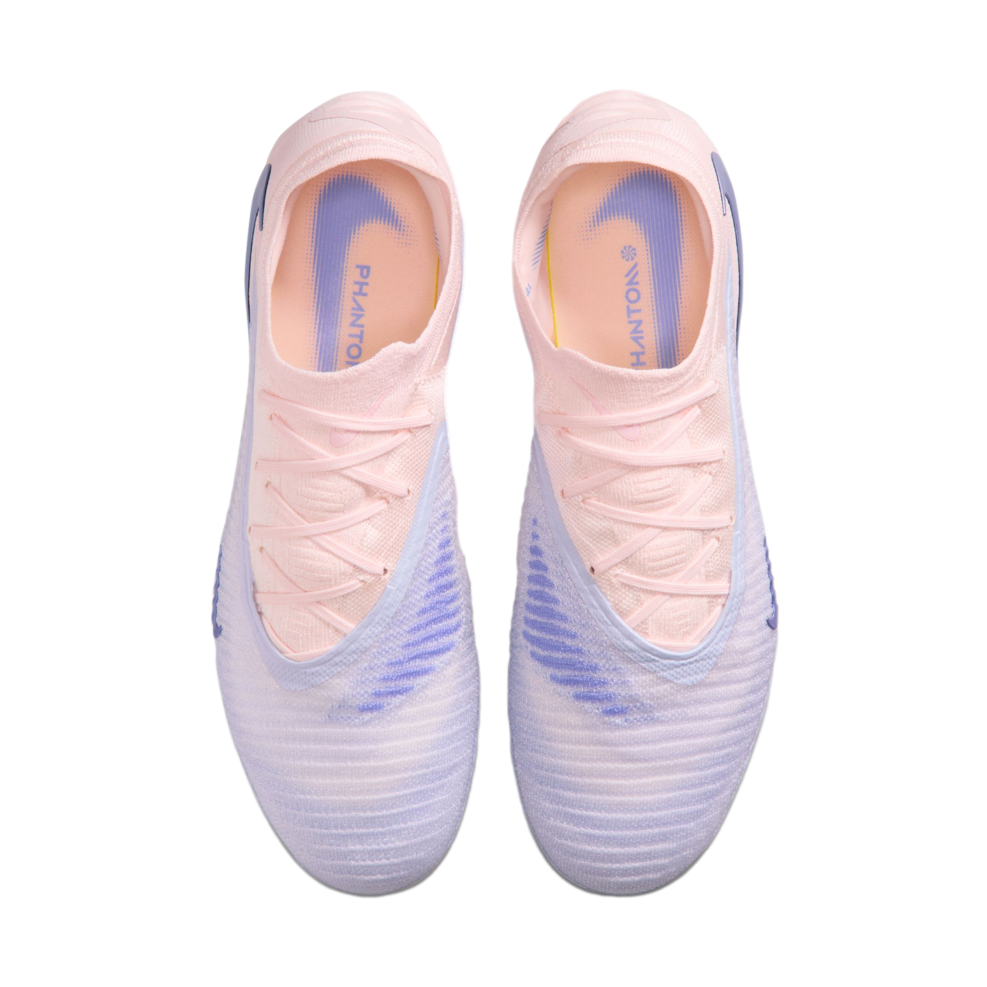 Top-down view of a pair of Nike Phantom soccer boots in pale pink and lavender against a black background.