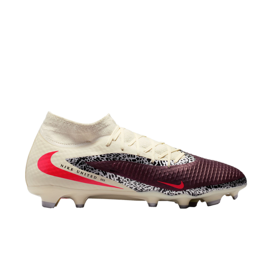 A side view of a Nike United soccer cleat featuring cream, maroon, and safari print panels with a large red swoosh, high-top collar, and "NIKE UNITED 003" text.