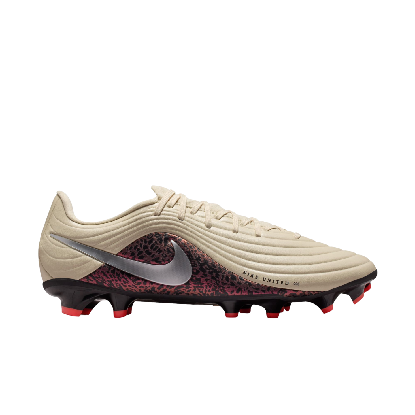 Side profile of a Nike United soccer cleat featuring a tan ridged upper, silver swoosh, and red-and-black patterned lower section against a black background.