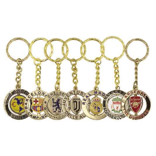 Seven gold-colored keychains featuring soccer club crests for Club América, Barcelona, Chelsea, Juventus, Real Madrid, Liverpool, and Arsenal.