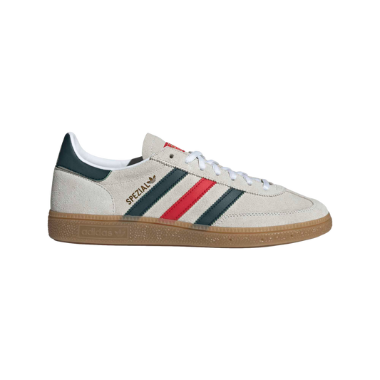A side profile of an Adidas Handball Spezial sneaker featuring an off-white suede upper, green and red stripes, and a gum rubber sole against a black background.