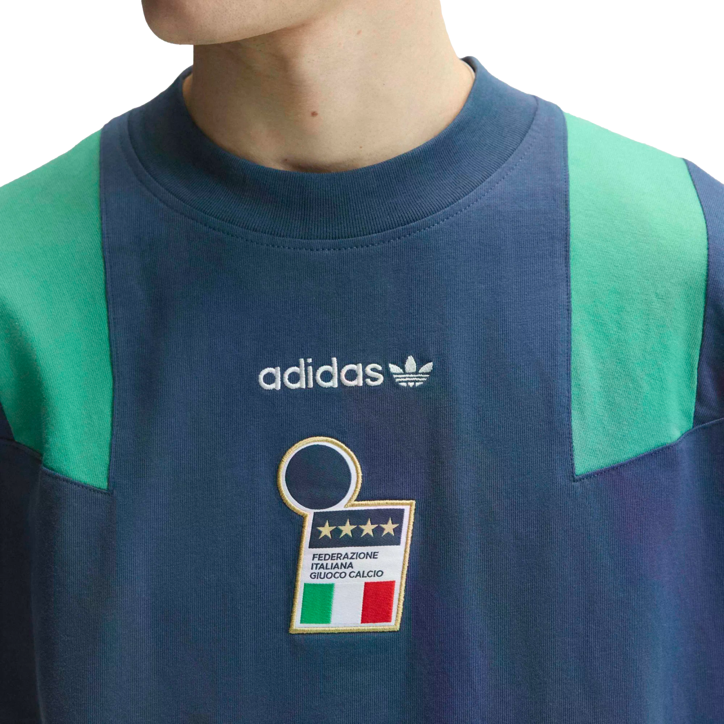 Close-up of a navy blue Adidas shirt with green shoulder panels, featuring the Adidas logo and the Italian national football team crest with four stars.