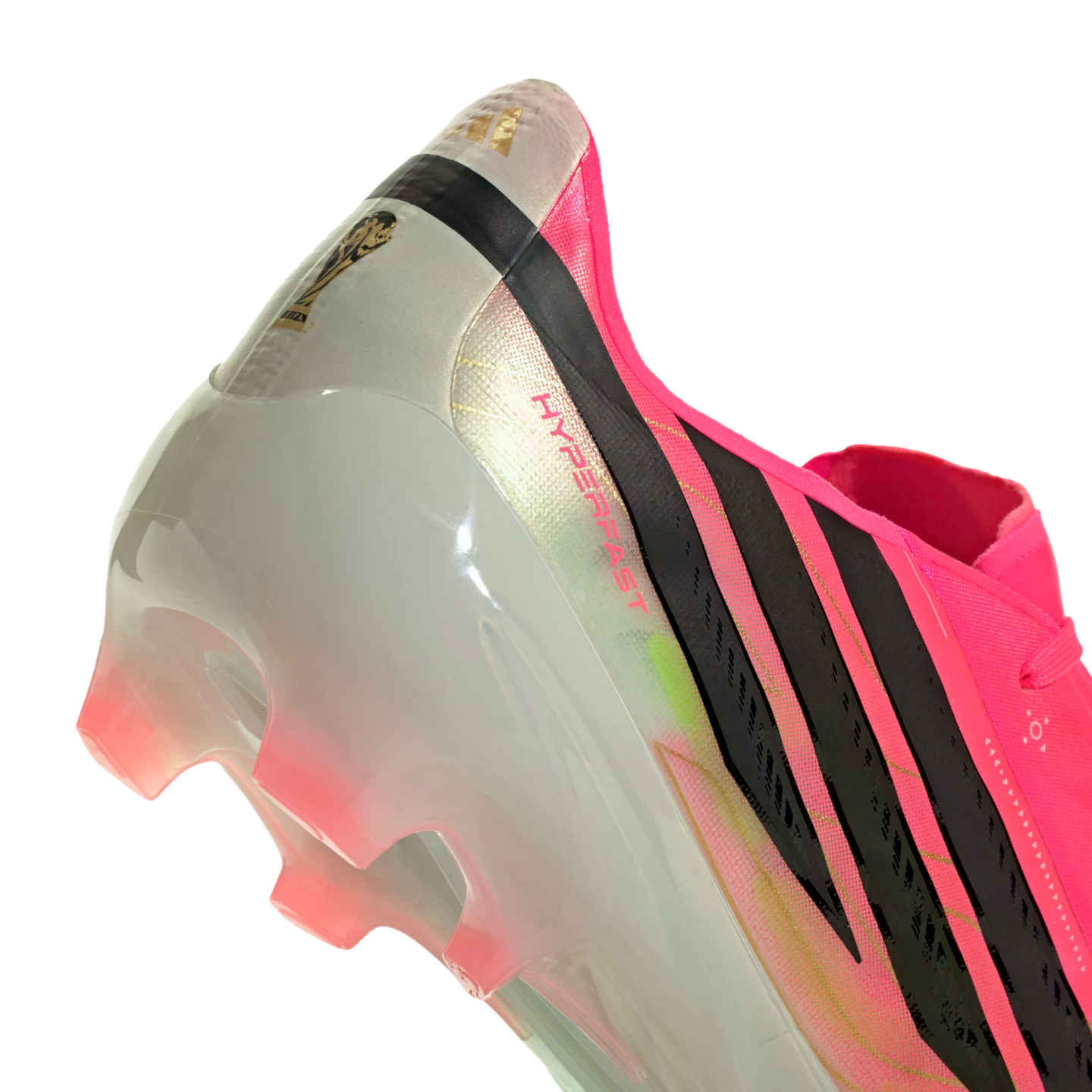 Close-up of the heel of a pink and white Adidas soccer cleat with black stripes, a gold FIFA logo, and translucent pink studs.