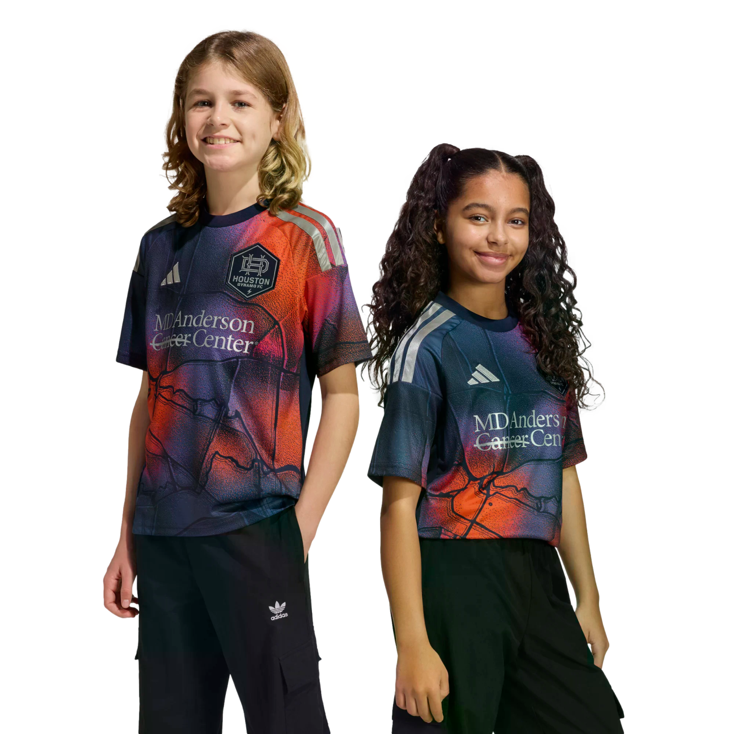 Two smiling children posing in vibrant Houston Dynamo FC soccer jerseys against a black background.
