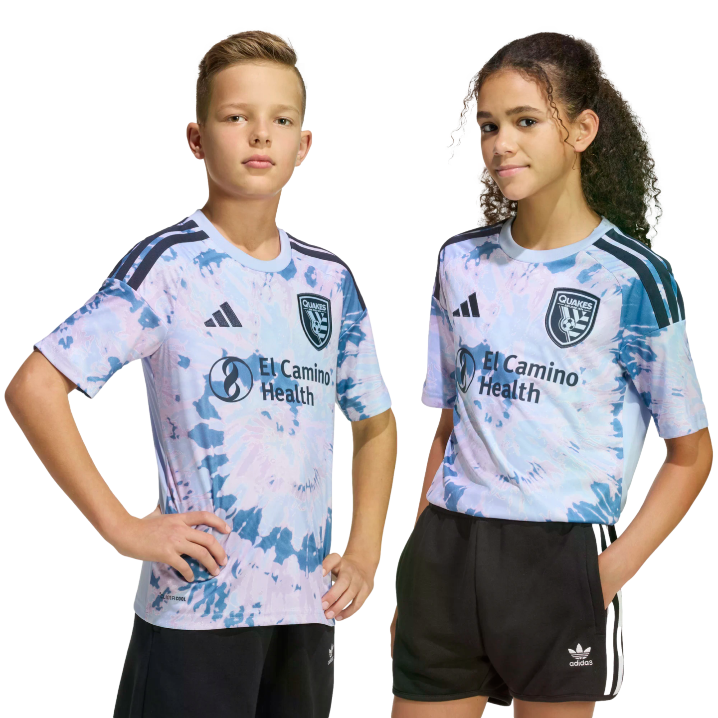 Two kids pose in matching light blue and pink tie-dye San Jose Earthquakes soccer jerseys and black shorts against a solid black background.