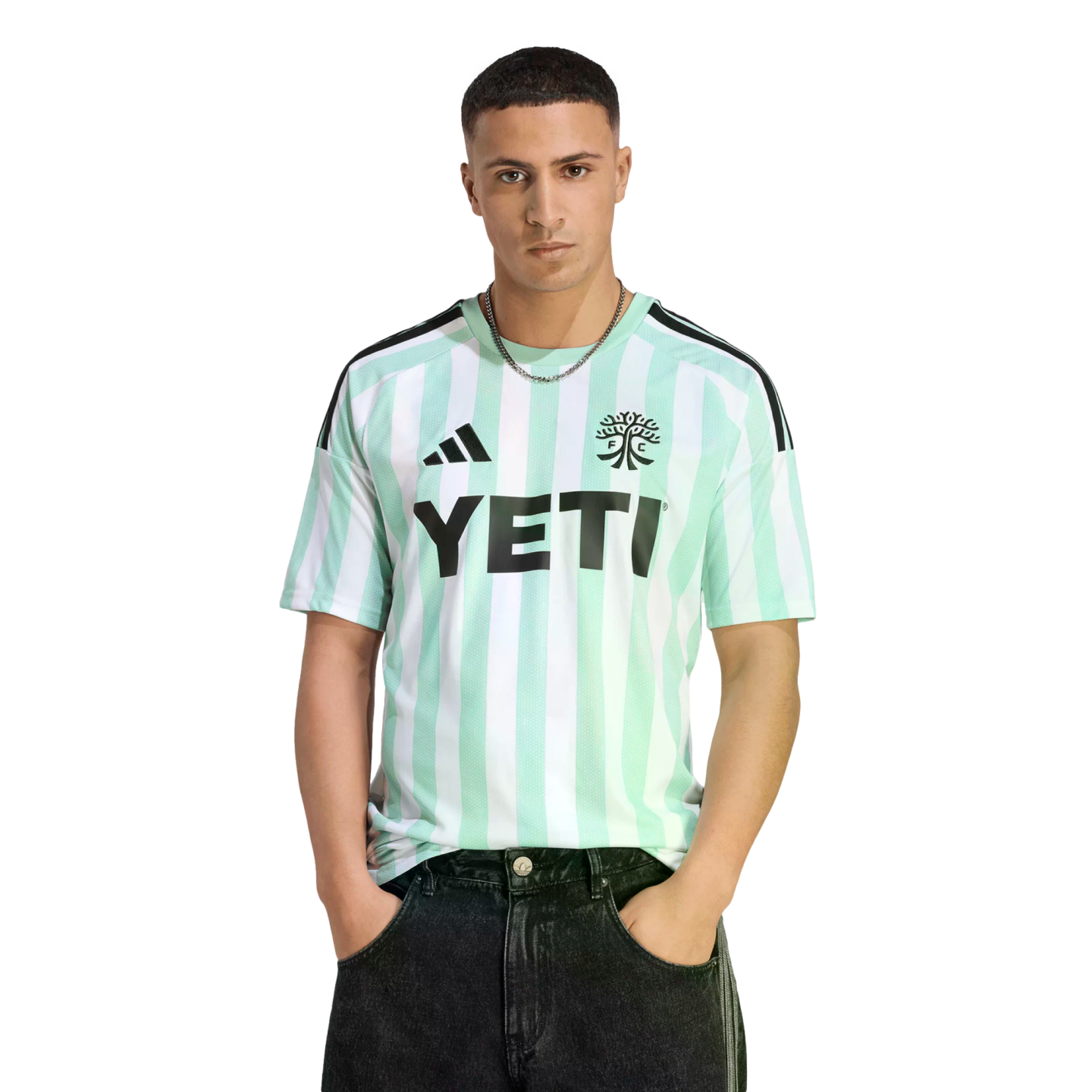 Man wearing a mint green and white striped soccer jersey with a black "YETI" logo on the chest, paired with black jeans against a black background.
