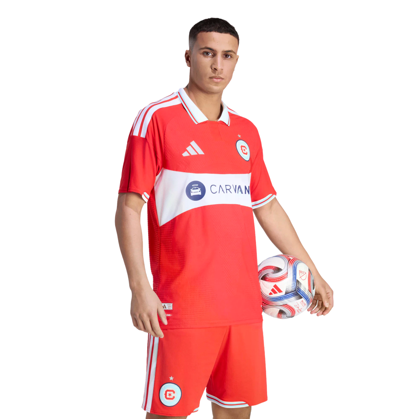 A male soccer player in a red Chicago Fire uniform holding a soccer ball against a black background.