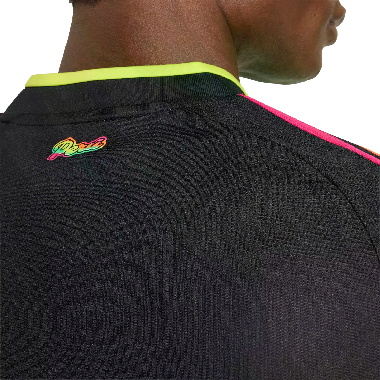 Close-up of a black Peru jersey back with a vibrant multicolored "Peru" logo, neon yellow collar trim, and pink shoulder stripes.