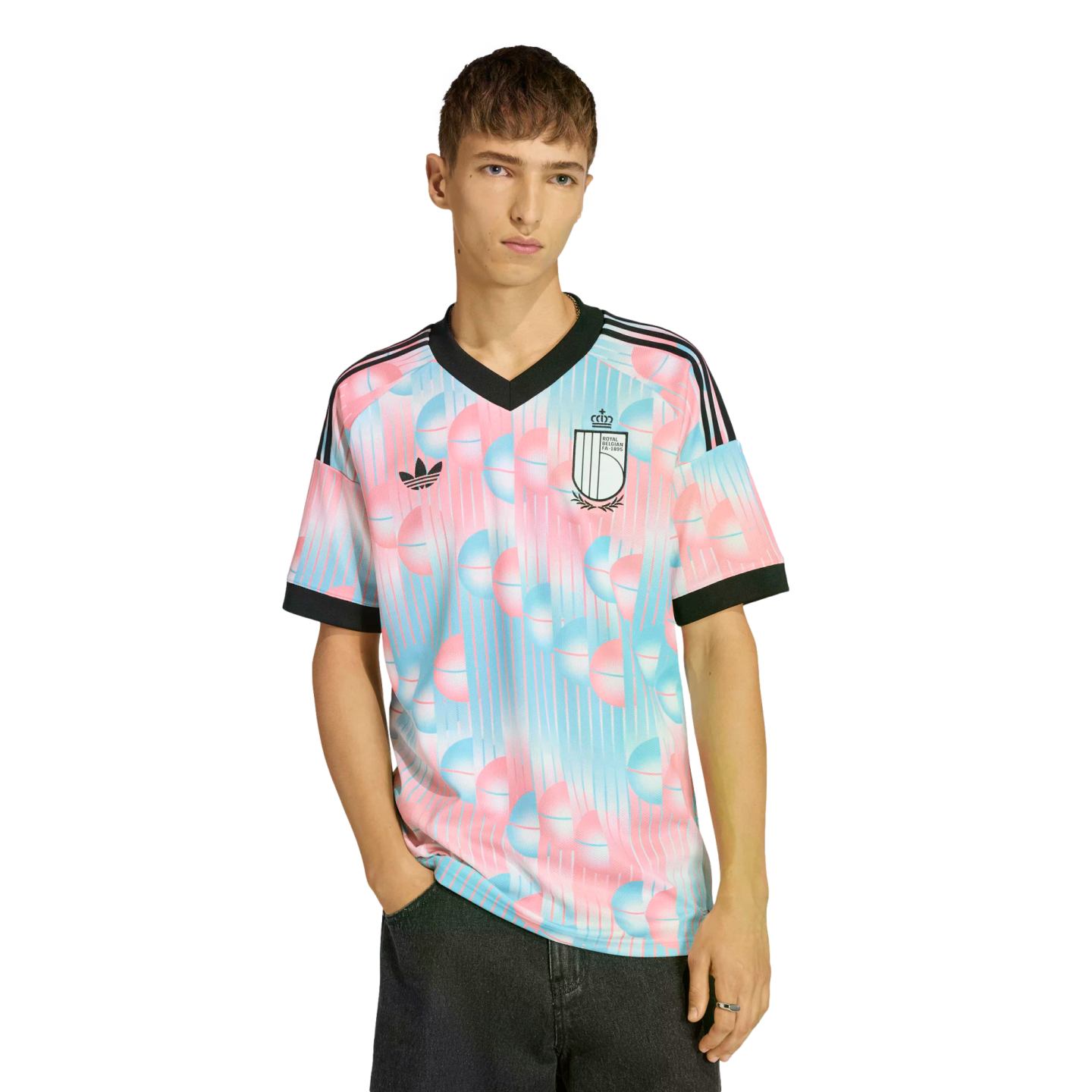 A man wearing a light blue and pink patterned Adidas Belgium soccer jersey with a black collar, set against a black background.