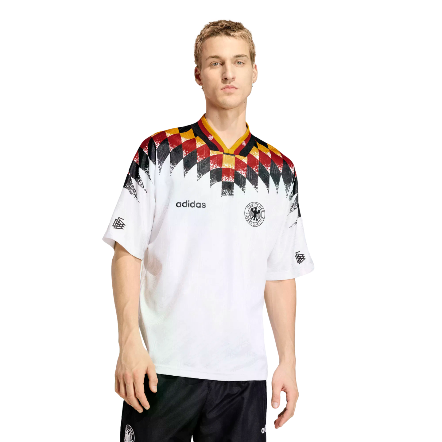 A man models a white Adidas Germany football jersey featuring a black, red, and yellow diamond pattern across the shoulders and neck.