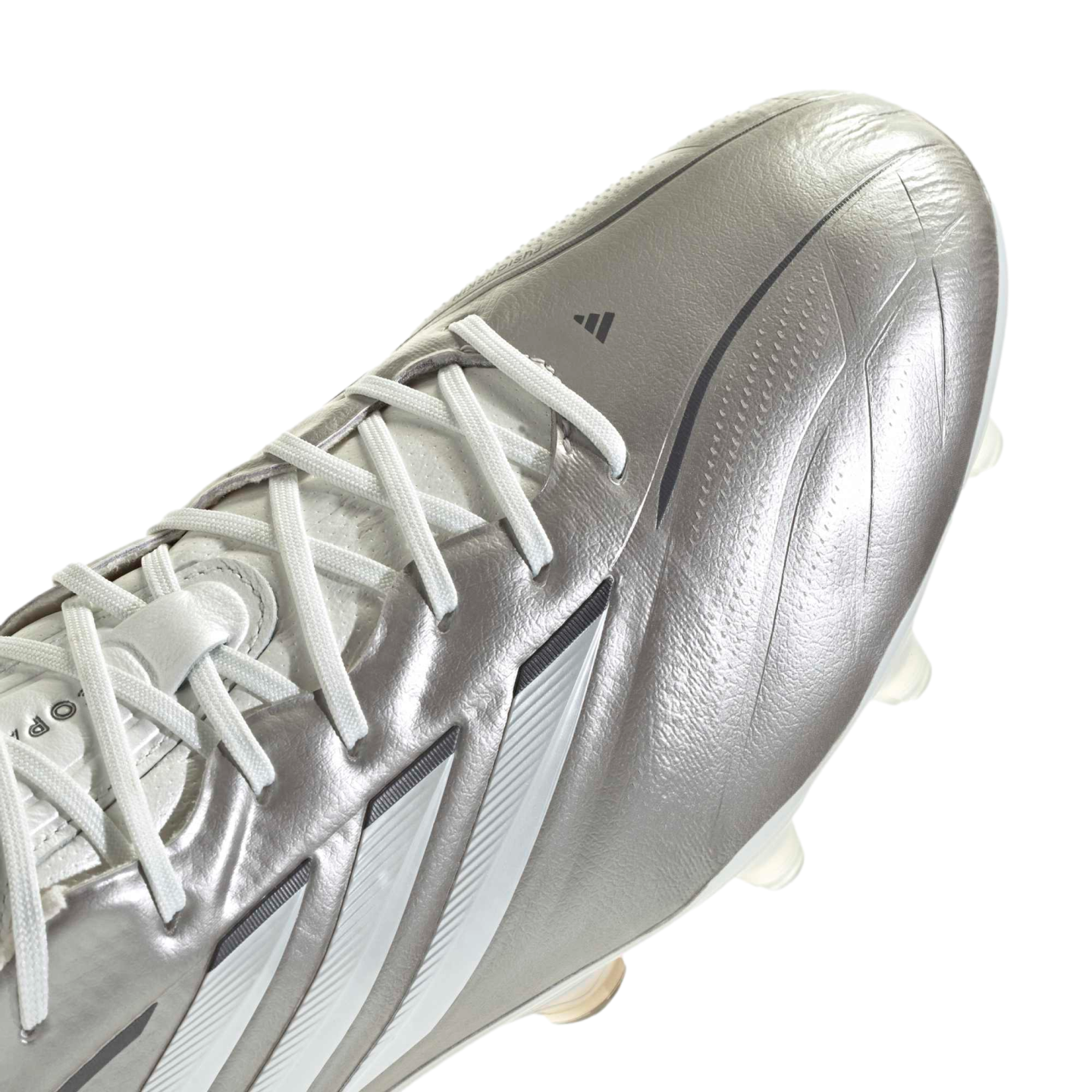 A close-up, angled view of a metallic silver Adidas soccer cleat against a solid black background. The cleat features white laces, three white stripes along the side, and a small black Adidas logo near the toe.