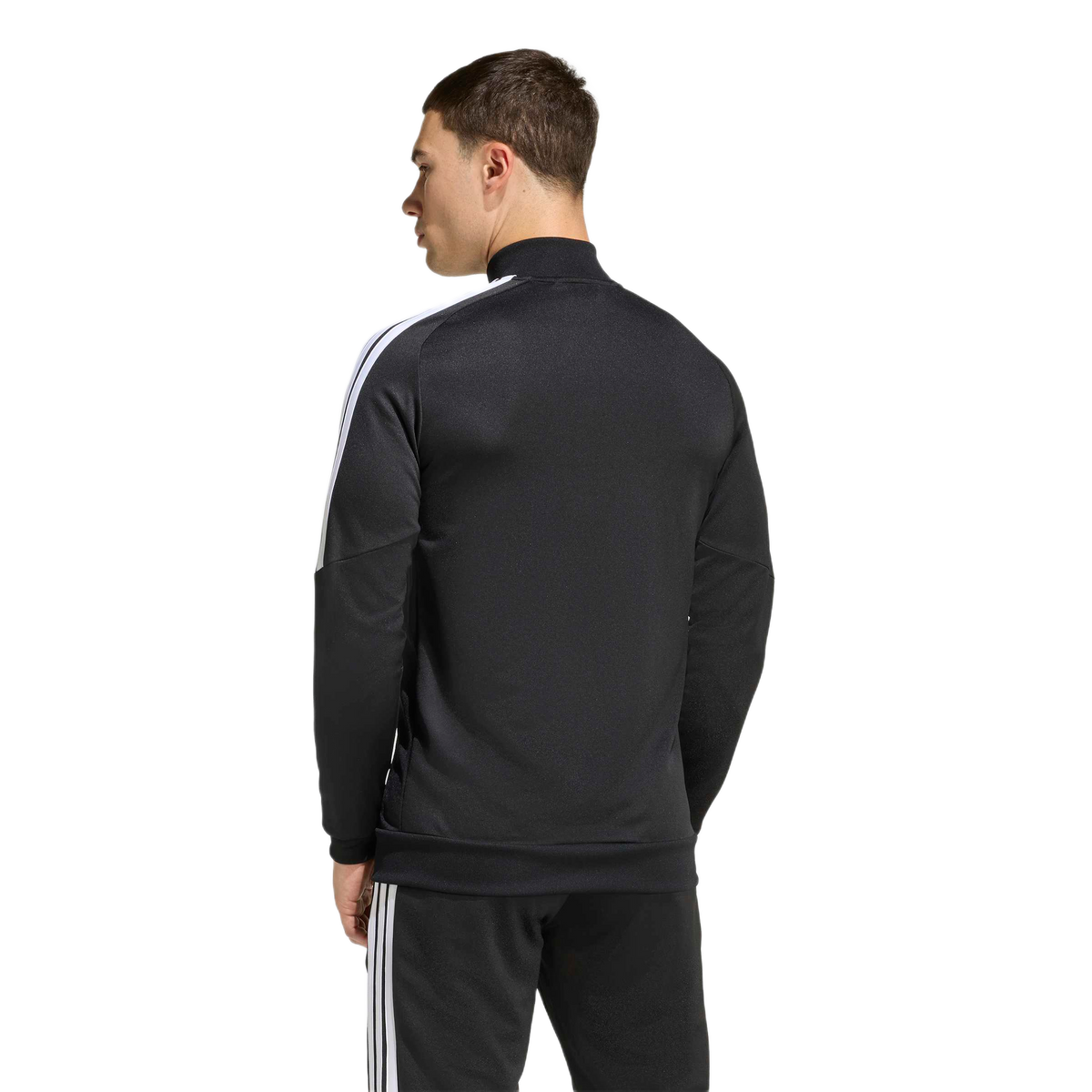 Rear view of a man wearing a black track jacket with white stripes on the shoulders and matching black pants, standing against a plain background.