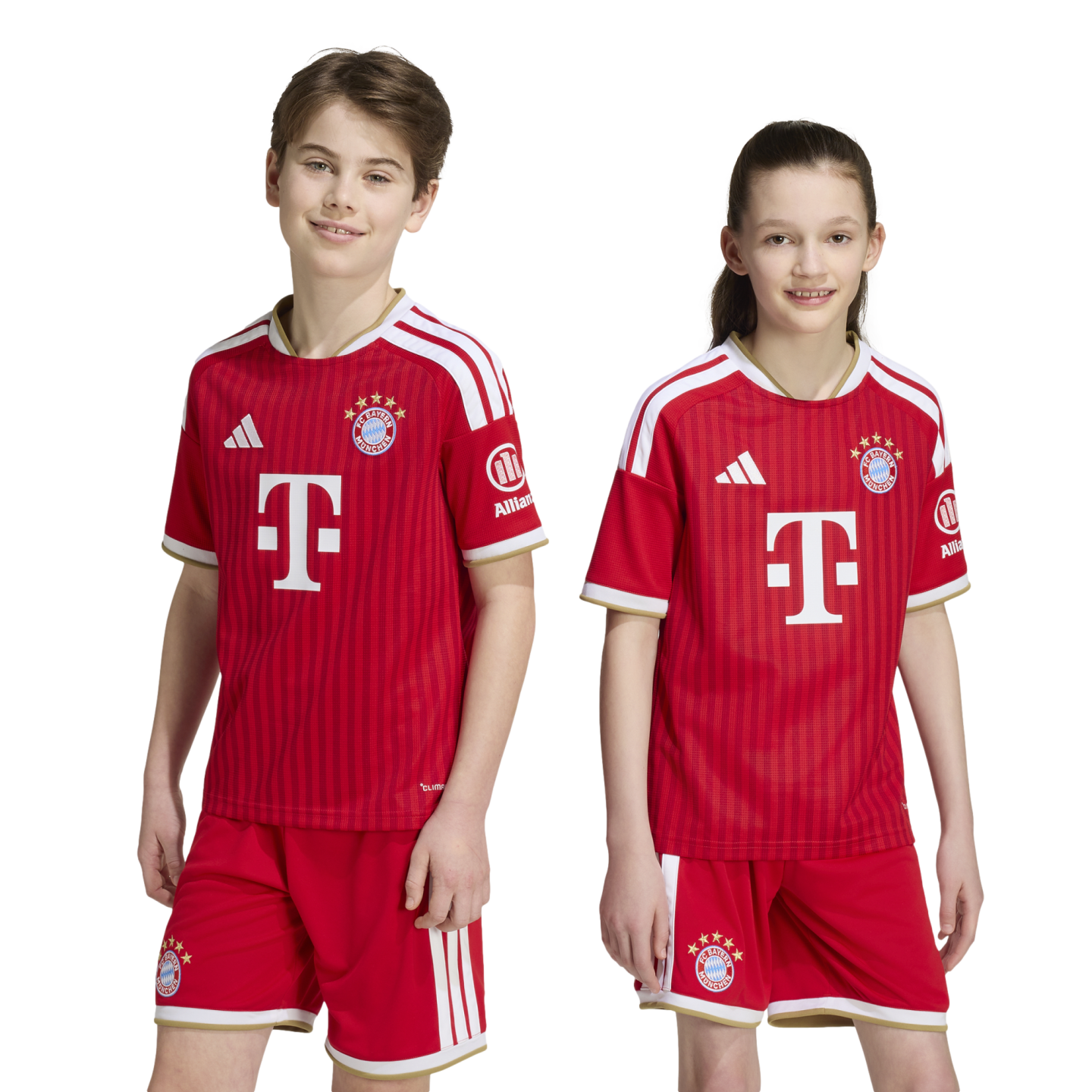 A boy and a girl smile wearing matching red FC Bayern Munich soccer uniforms, featuring the team's crest and sponsor logos, against a white background.