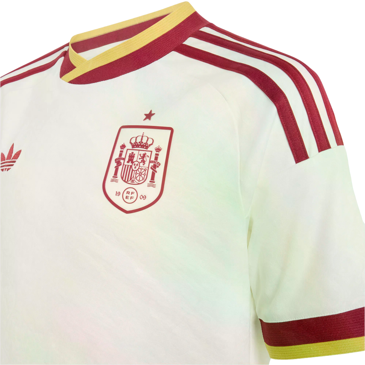 A close-up of a cream-colored Spain national football team jersey. It features a maroon team crest on the chest topped with a single star, maroon and yellow trim on the v-neck collar and sleeve cuffs, and maroon Adidas stripes on the shoulder.