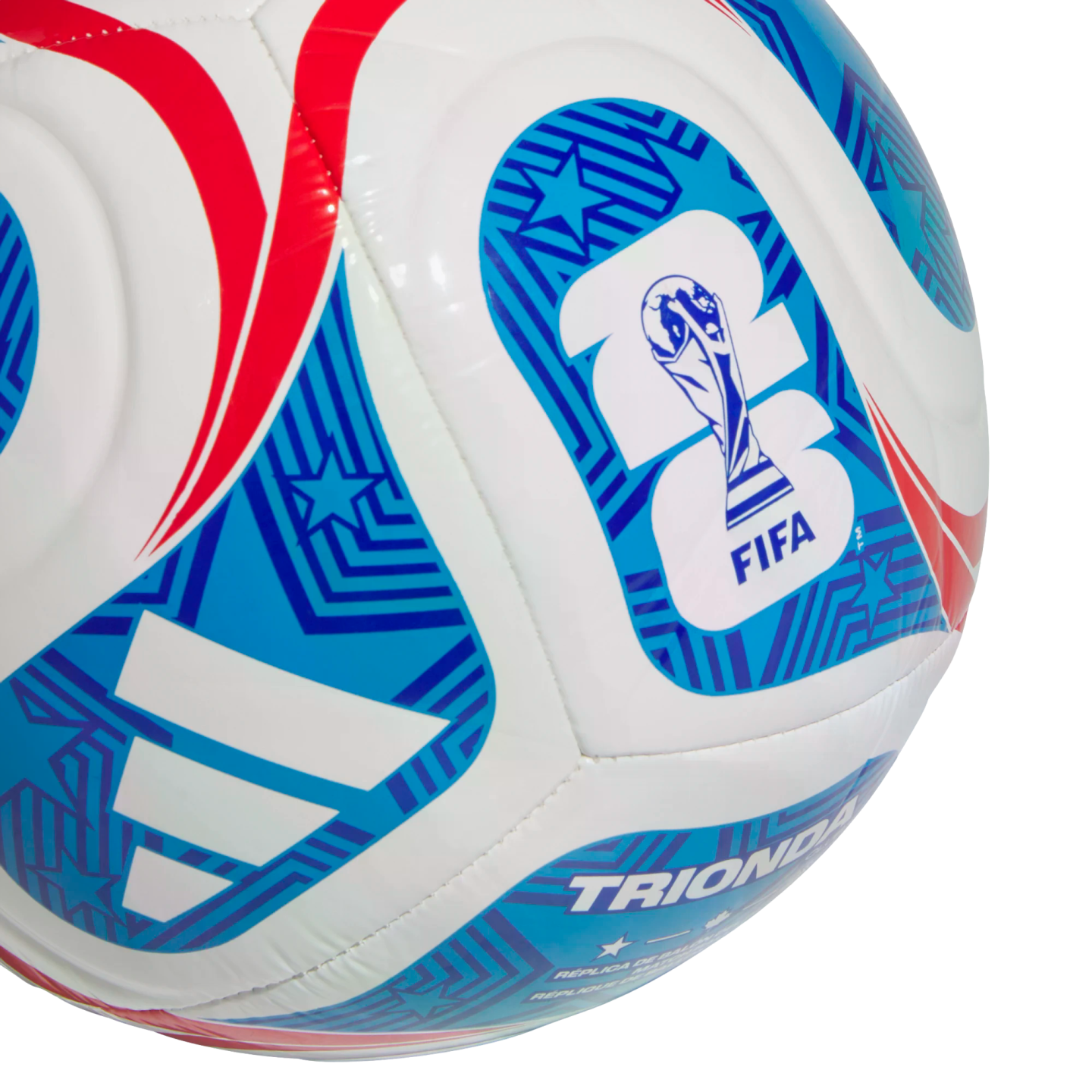A close-up of a white Adidas soccer ball featuring red and blue graphics, the FIFA World Cup 2026 logo, and the word "TRIONDA."