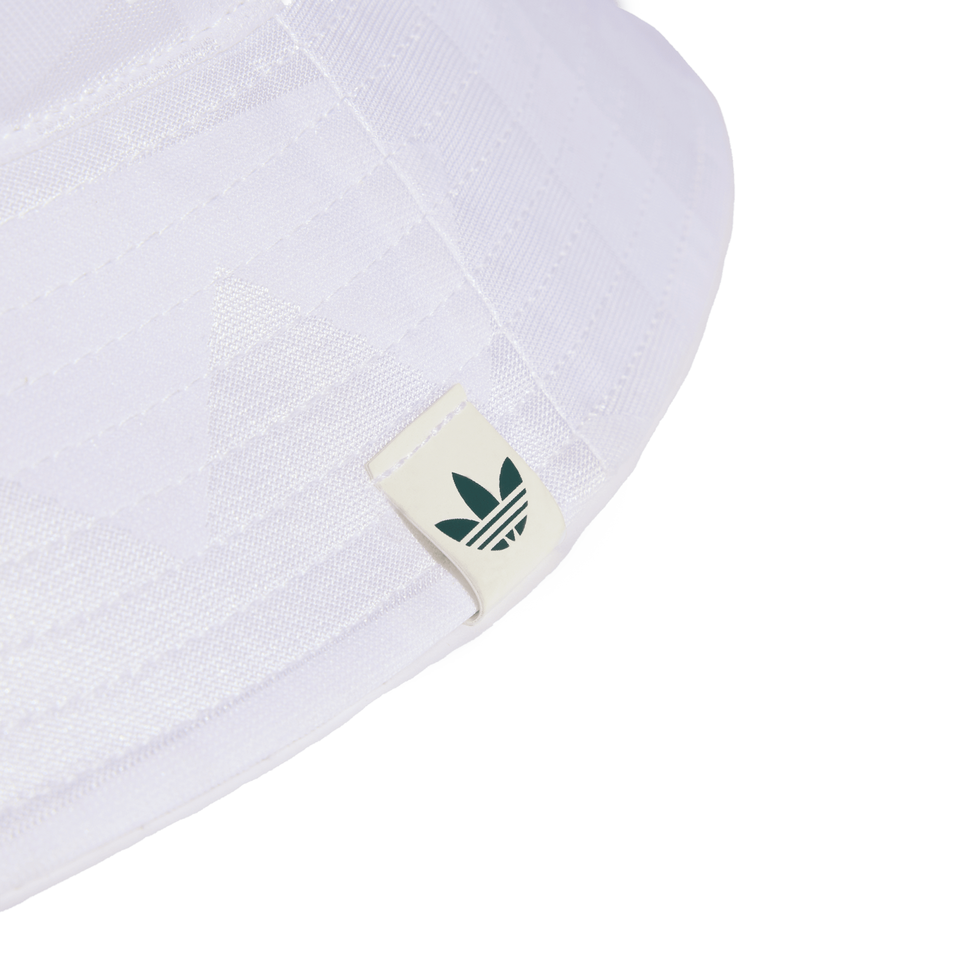 Close-up of the brim of a white bucket hat featuring a small off-white tag with a dark green Adidas Trefoil logo. Set against a solid black background.