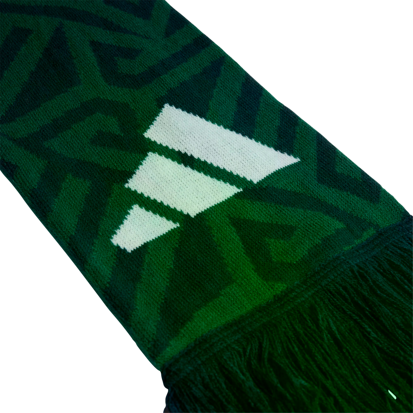 Close-up of a green knitted scarf with a white three-stripe logo, dark geometric patterns, and a fringed edge against a black background.