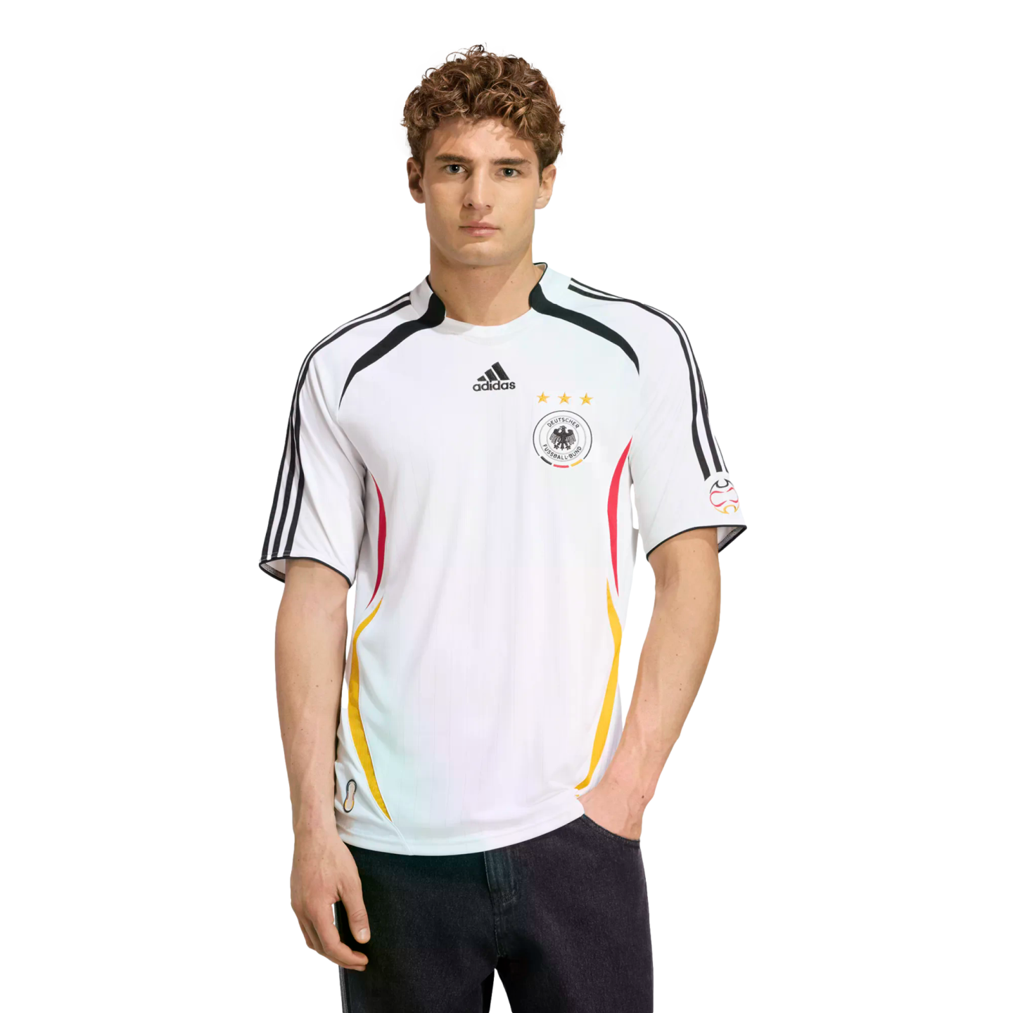 A man models a white Adidas Germany national soccer team jersey and dark jeans against a plain white background.