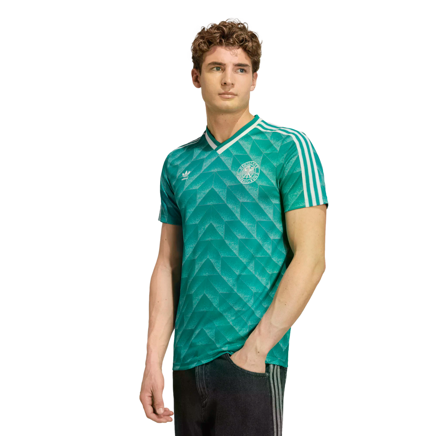 A young man wearing a green Adidas Germany soccer jersey with a white geometric pattern, standing against a white background.