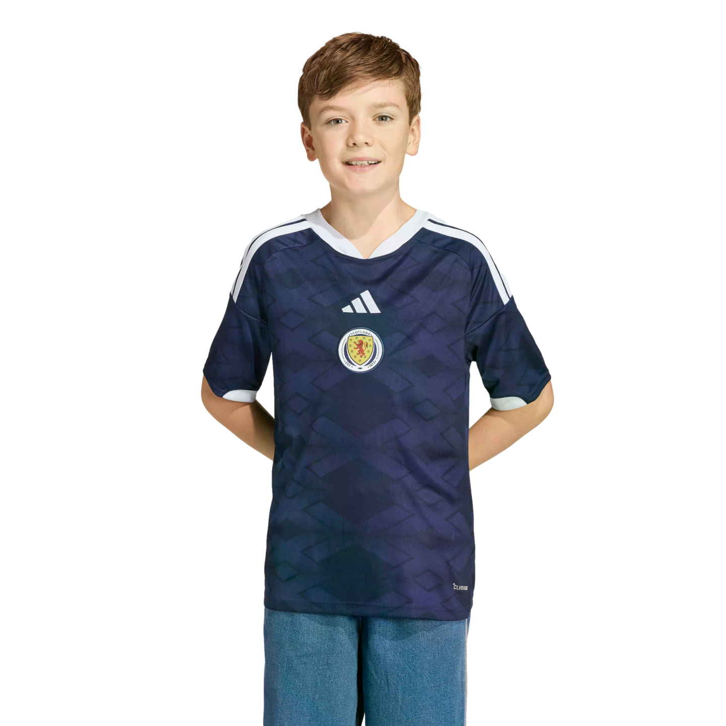 A young boy smiles while wearing a navy blue Scotland national football team jersey against a black background.