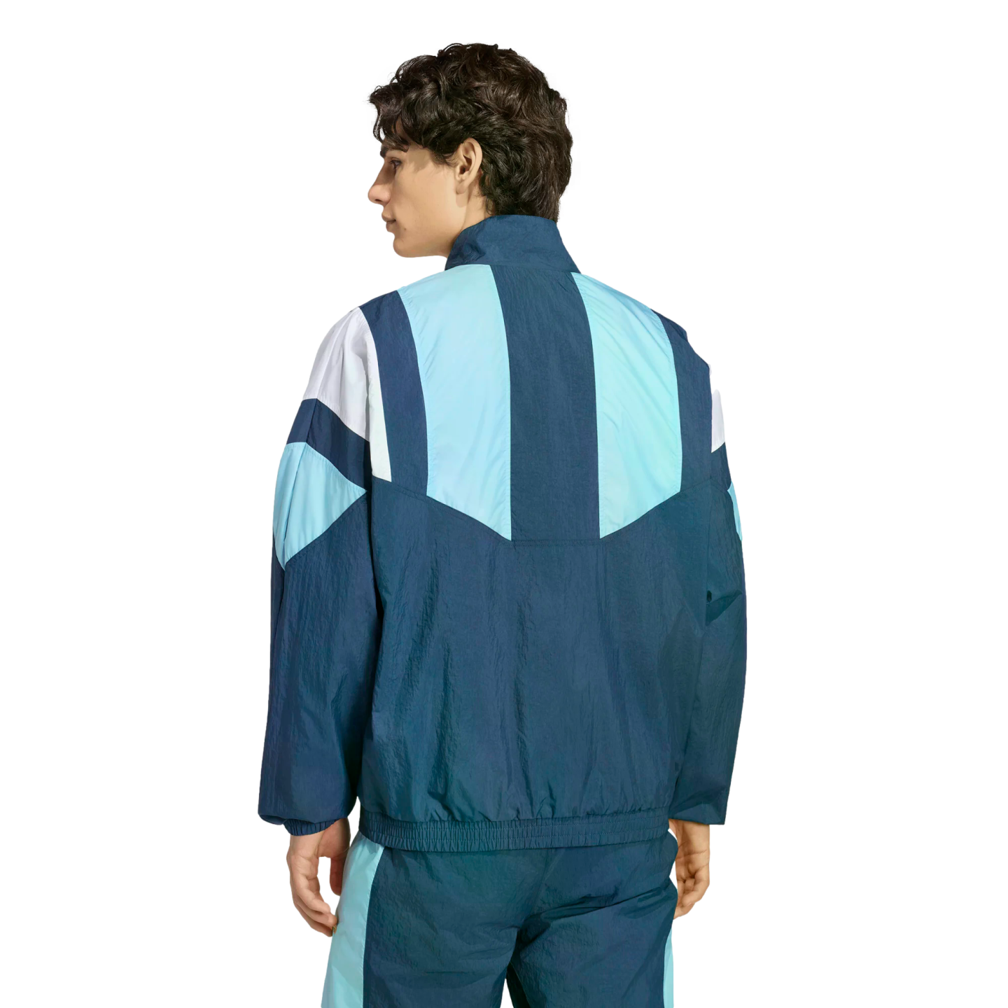 Rear view of a man wearing a blue and white geometric color-blocked windbreaker and matching track pants against a plain white background.