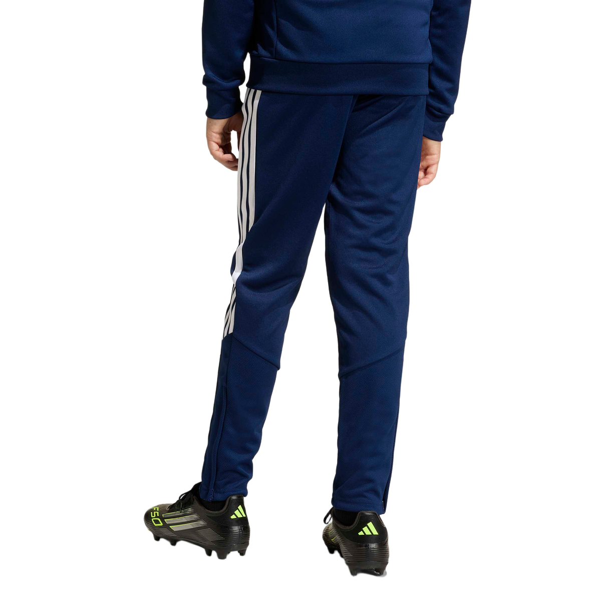 Rear view of navy blue Adidas track pants with white side stripes, paired with black soccer cleats.