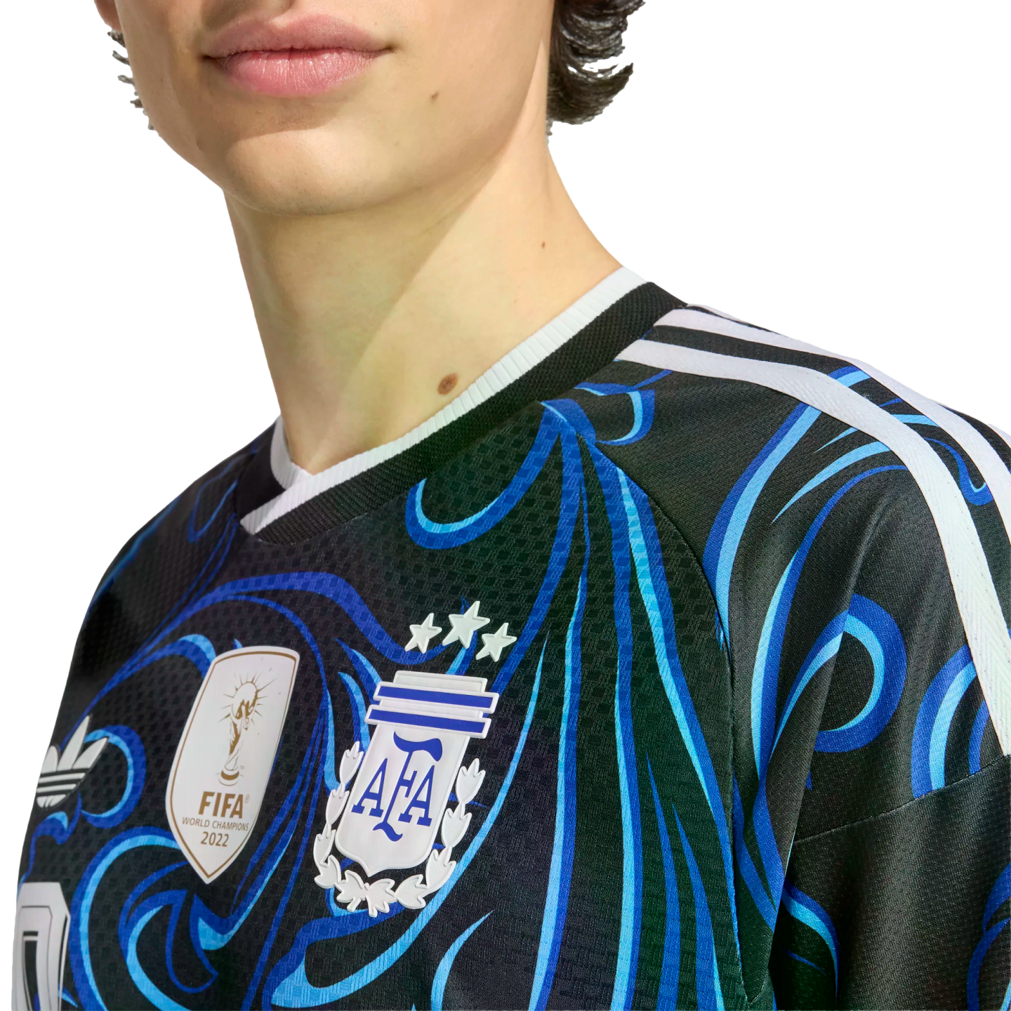 Close-up of a person wearing a black and blue patterned Argentina football jersey, featuring the AFA crest with three stars and the FIFA World Champions 2022 gold patch.