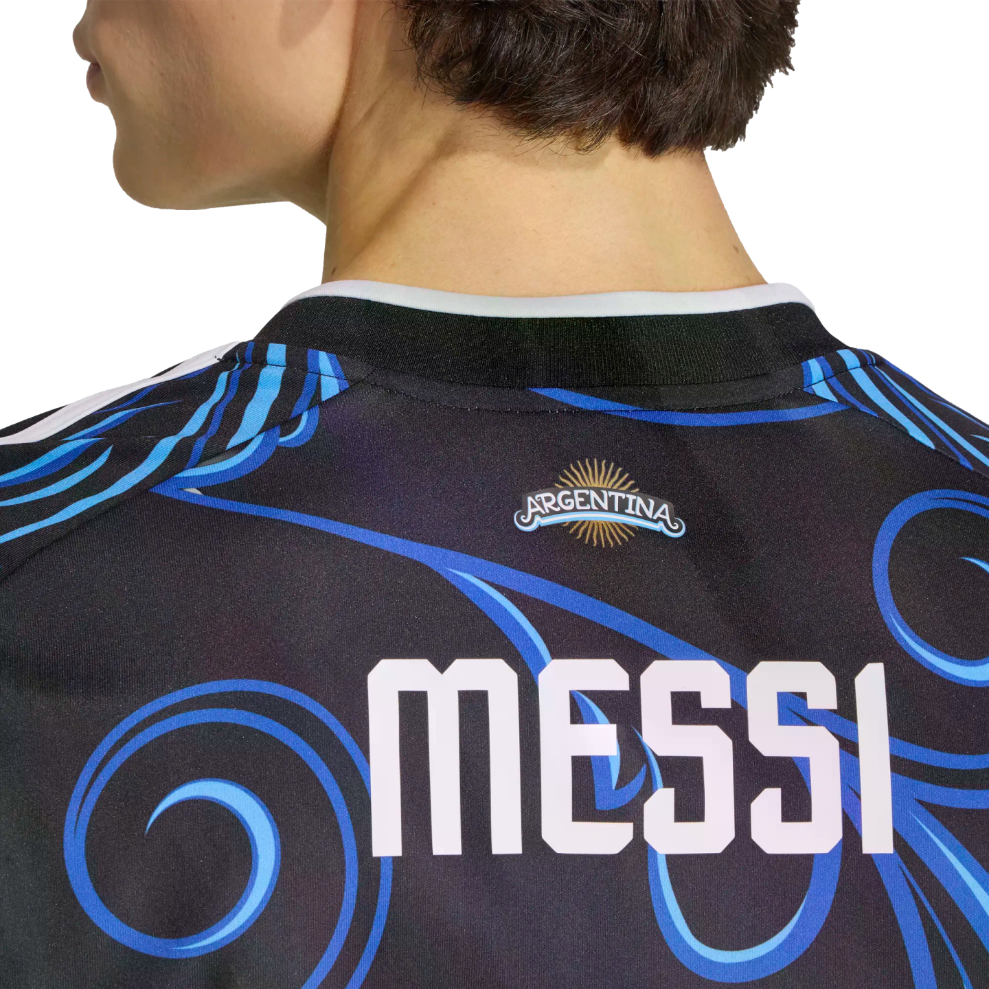 Back view of a dark soccer jersey with blue swirls, featuring the name "MESSI" in large white letters below an Argentina logo with a gold sun.