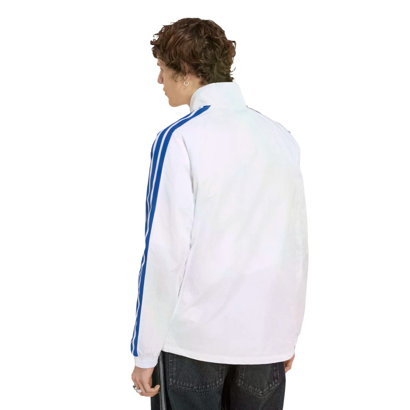 Back view of a person with curly brown hair wearing a white jacket with blue stripes on the sleeves and dark jeans, set against a black background.