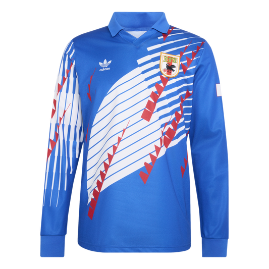 A blue long-sleeved Adidas jersey with a white and red geometric design, featuring a collared neck, Adidas trefoil logo, and a team crest on the chest.