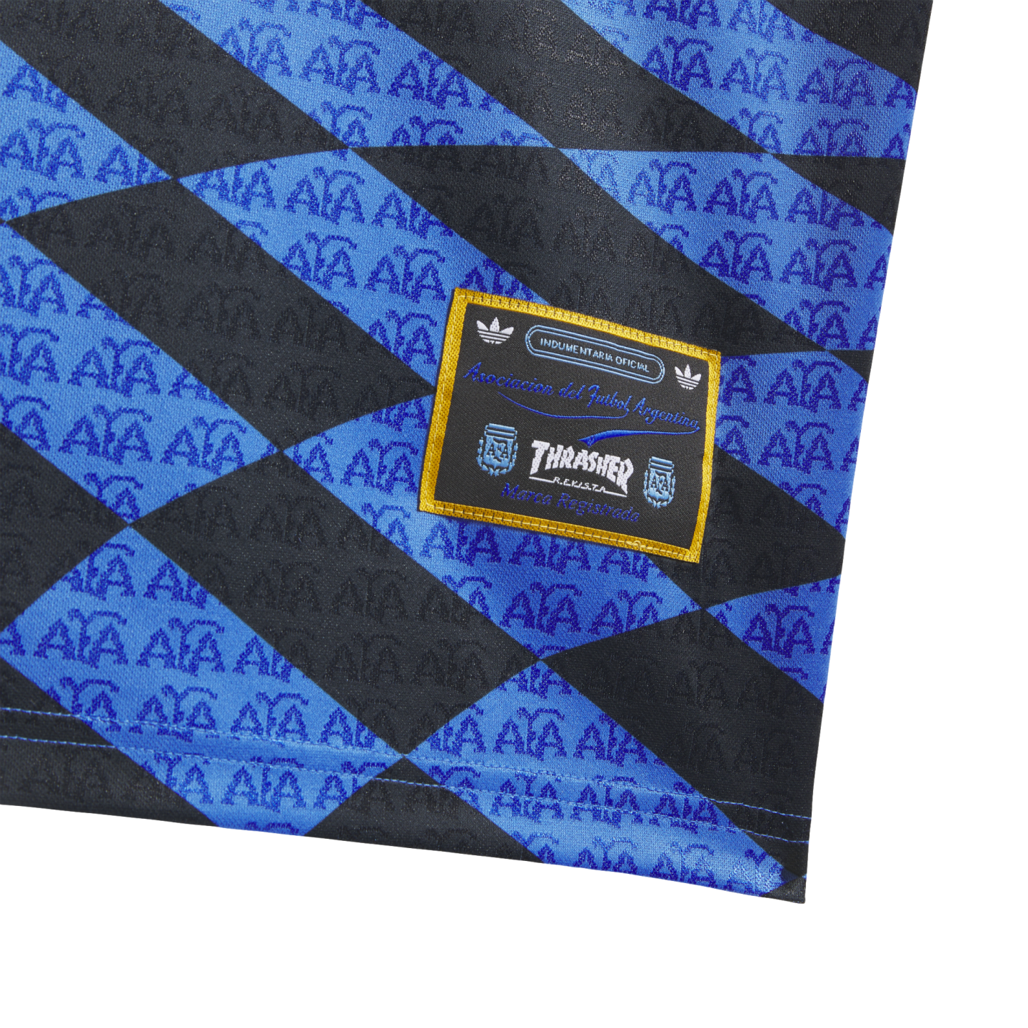 Close-up of a blue and black diamond-patterned fabric with repeated AFA logos and a yellow-bordered Thrasher and Argentine Football Association patch.