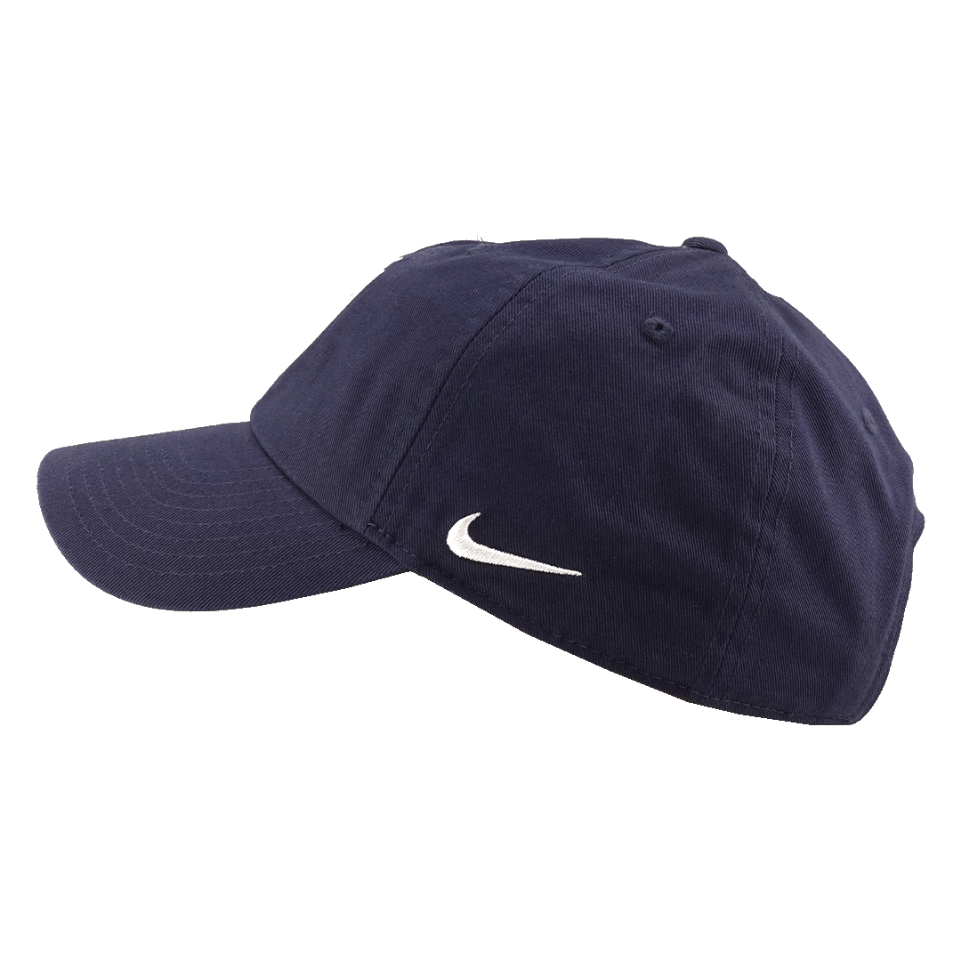 A side view of a navy blue Nike baseball cap with a white swoosh logo, set against a solid green background.
