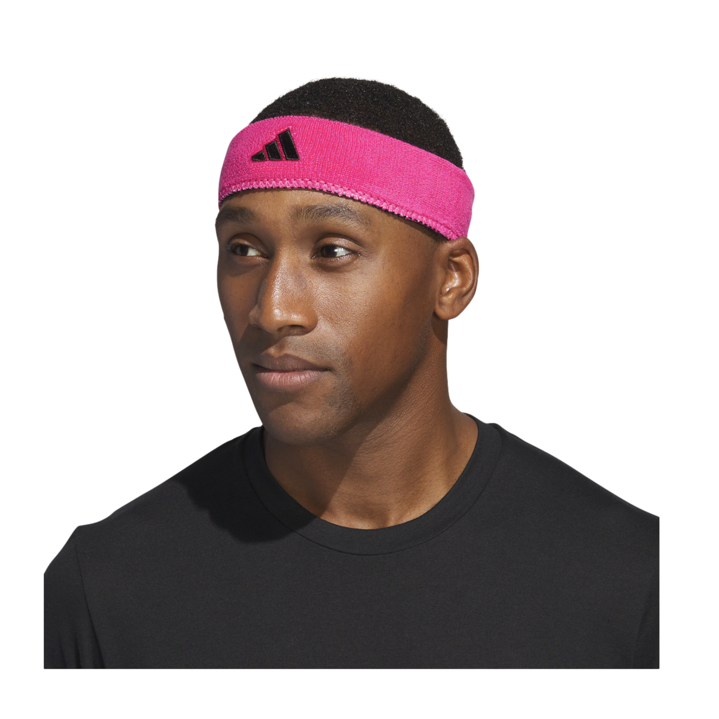 Close-up of a man wearing a bright pink Adidas headband and a black t-shirt against a black background.